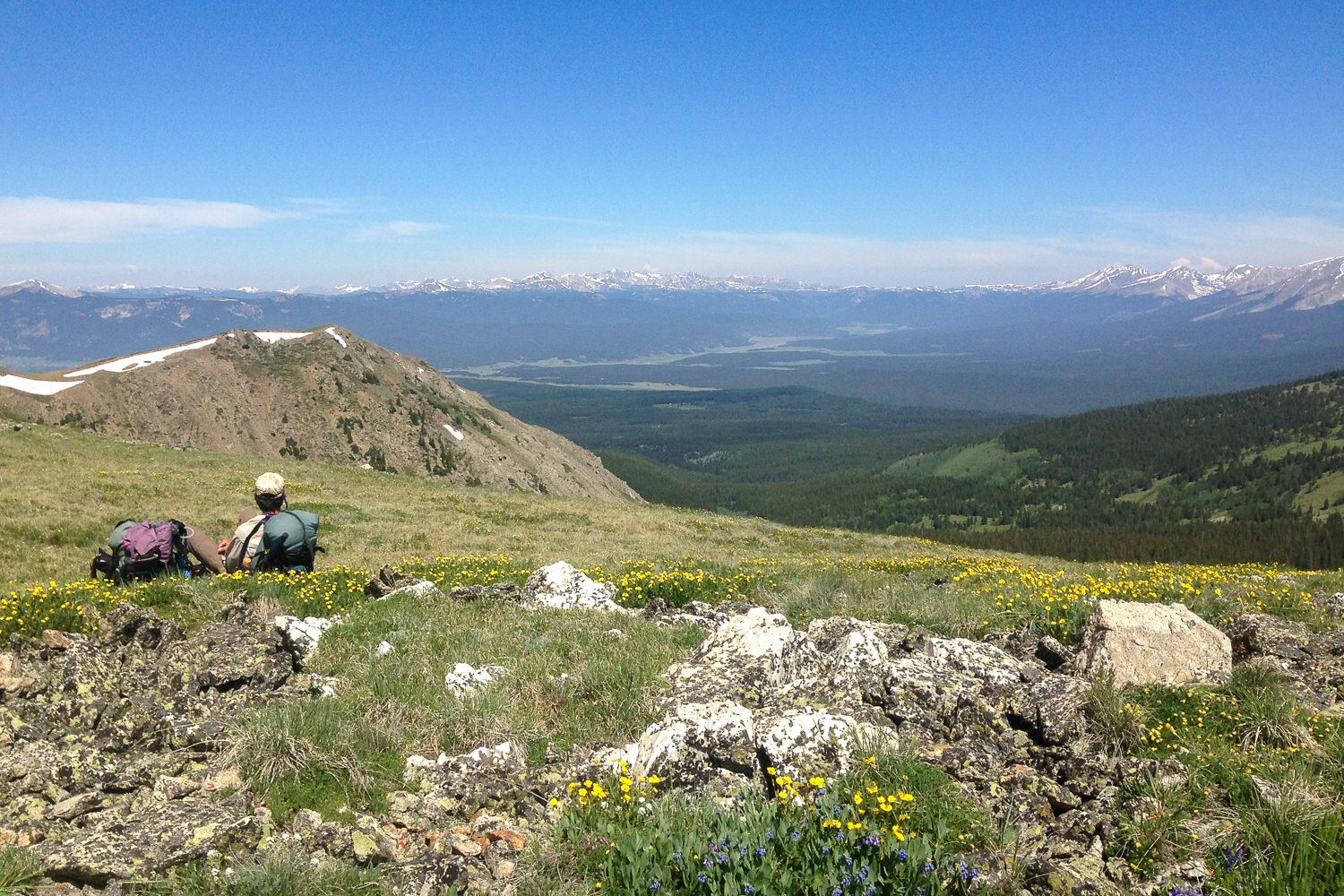 backpacker resting their back on their pack while looking out over a mountain range.