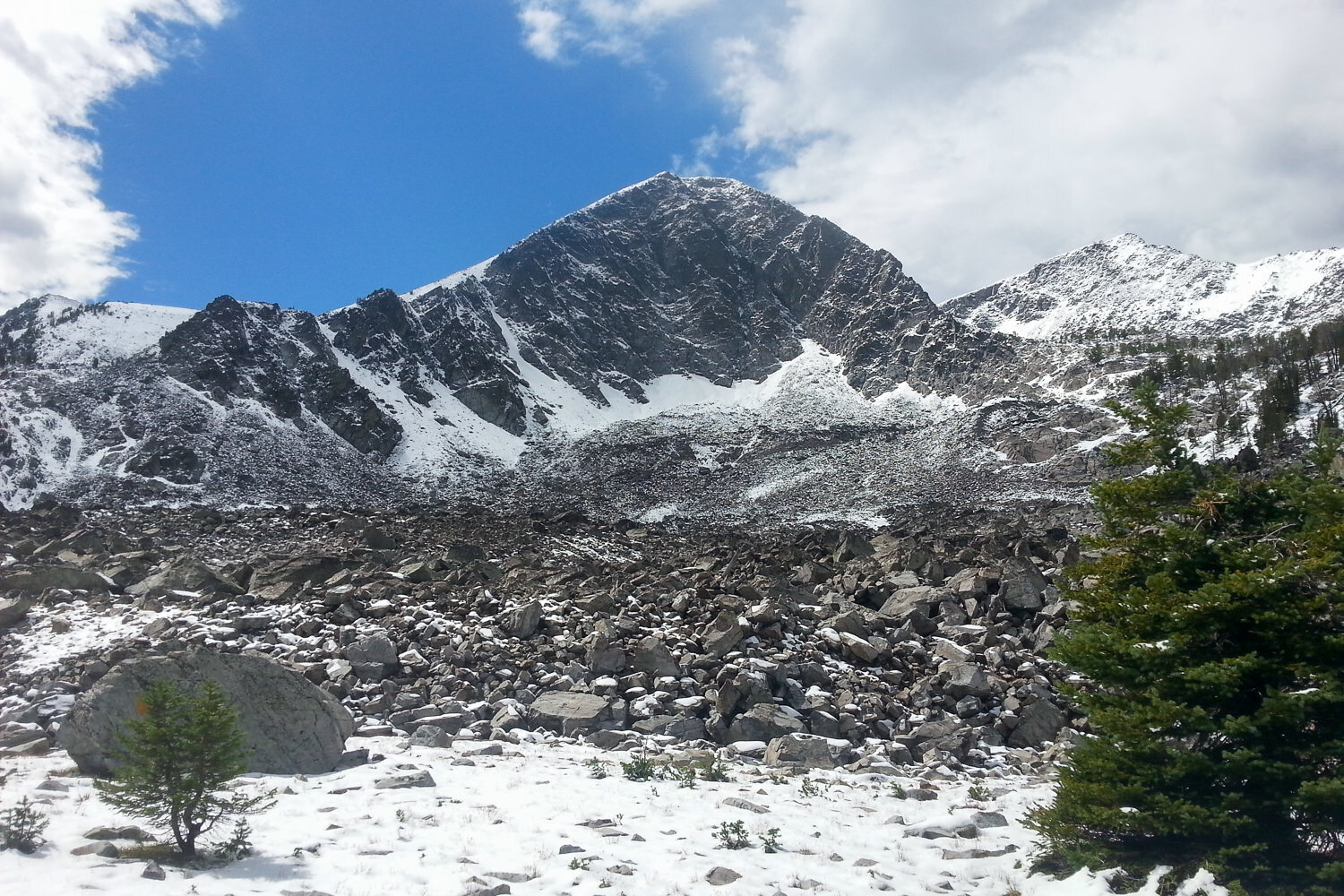 snow dusted mountain with blue skies and clouds over it.
