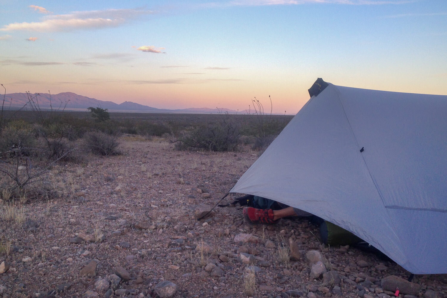 tent set up with the sun setting on high desert landscape