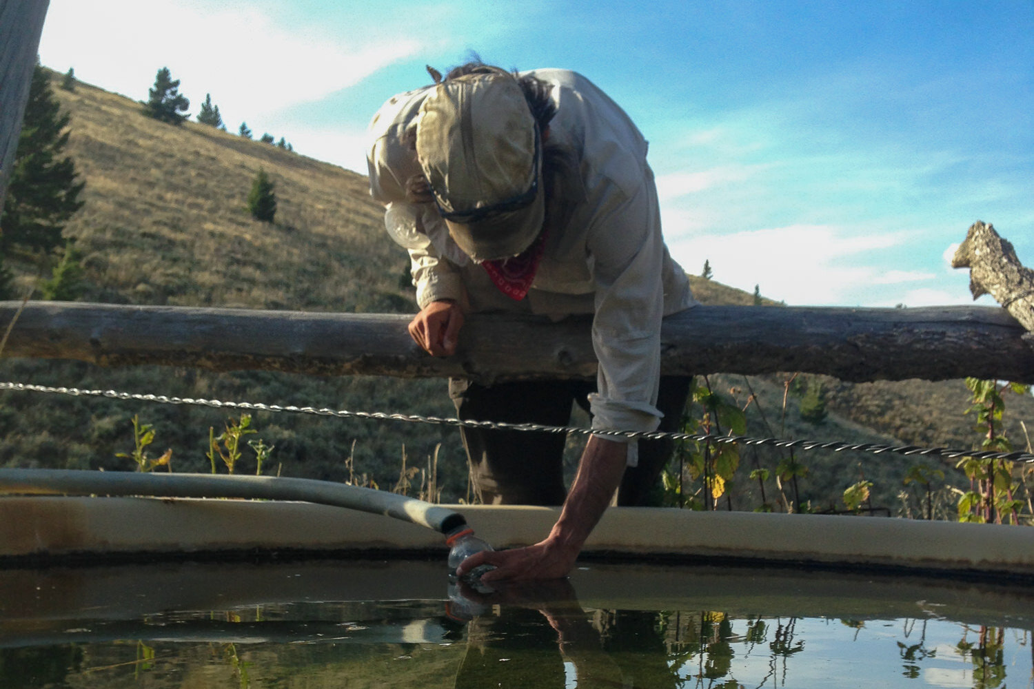 CDT hiker filling a water bottle from a stock tank.