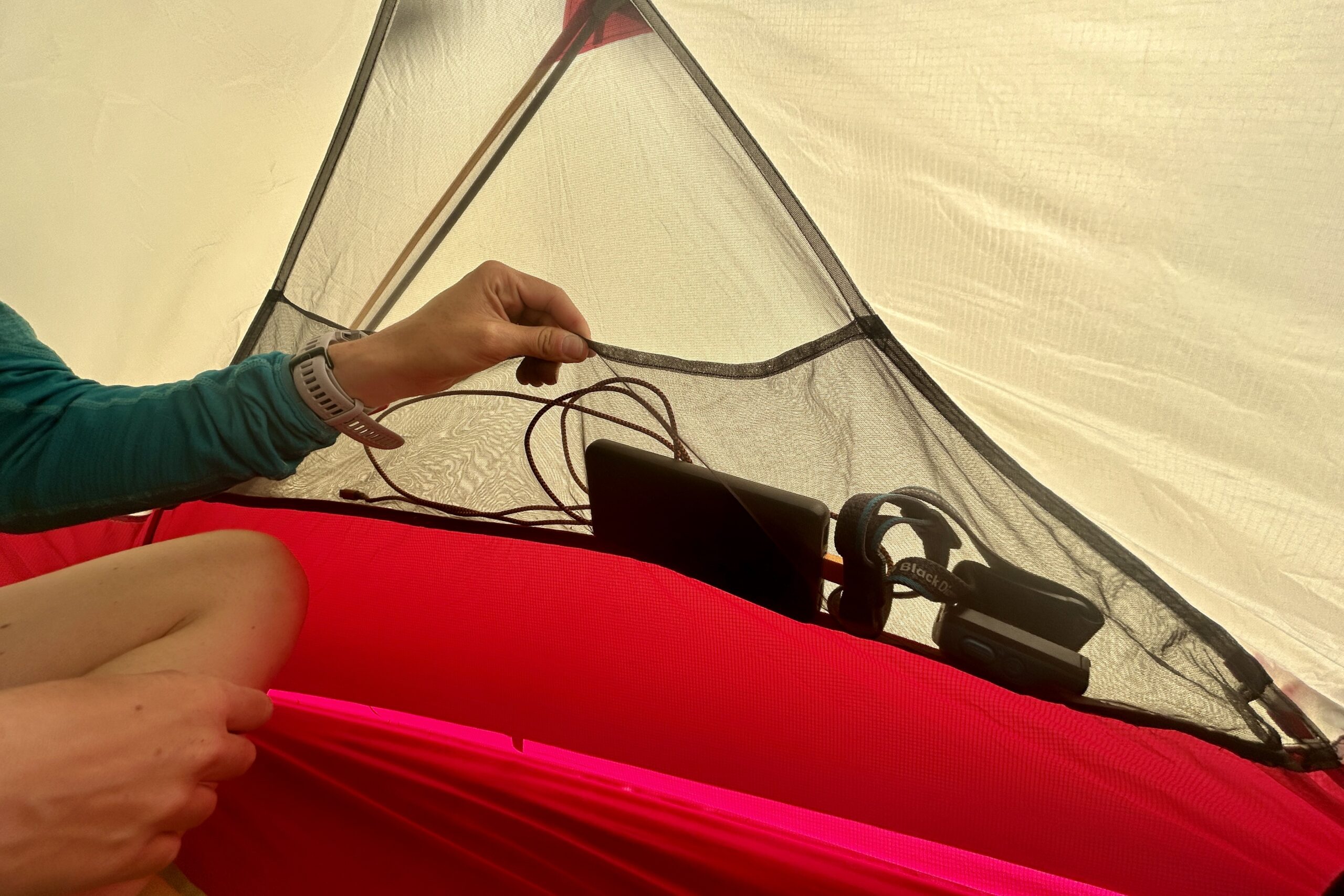 A closeup of the wide internal pocket of a tent with items in it.