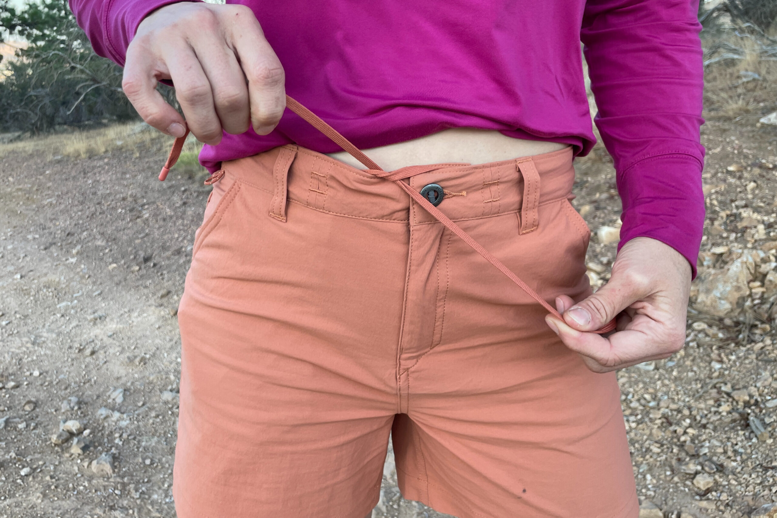 a close up of the front of the patagonia quandary shorts with the women holding the drawstrings to tighten the waist