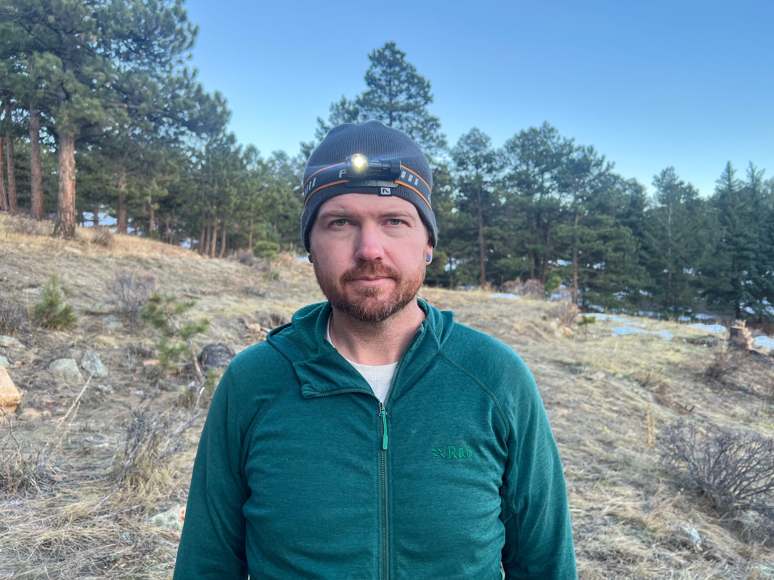 The image shows a person wearing the Fenix HM50R V2.0 headlamp while standing outdoors in a mountainous area.