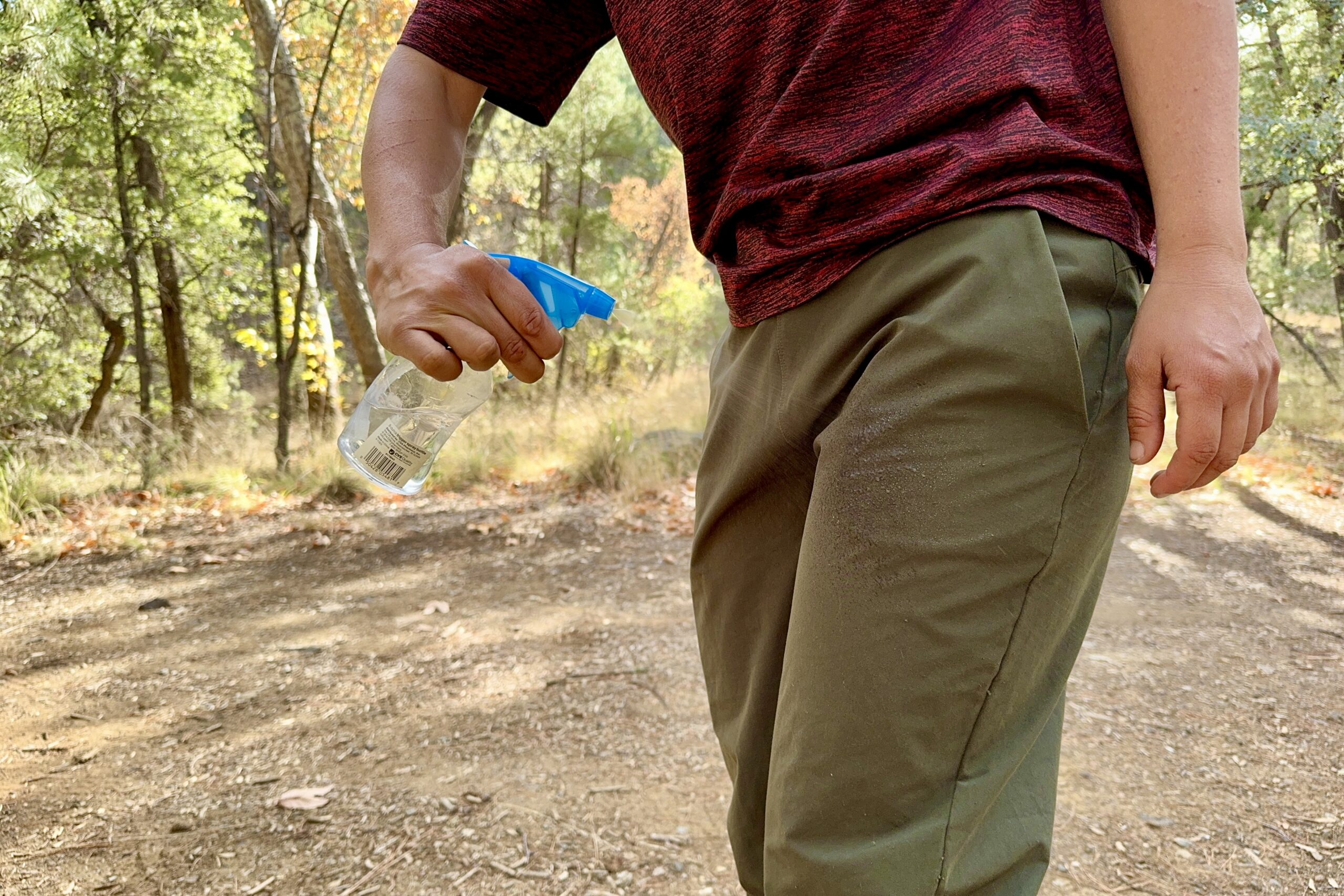 A hand is spraying the Patagonia Happy Hike pants with water from a squirt bottle.