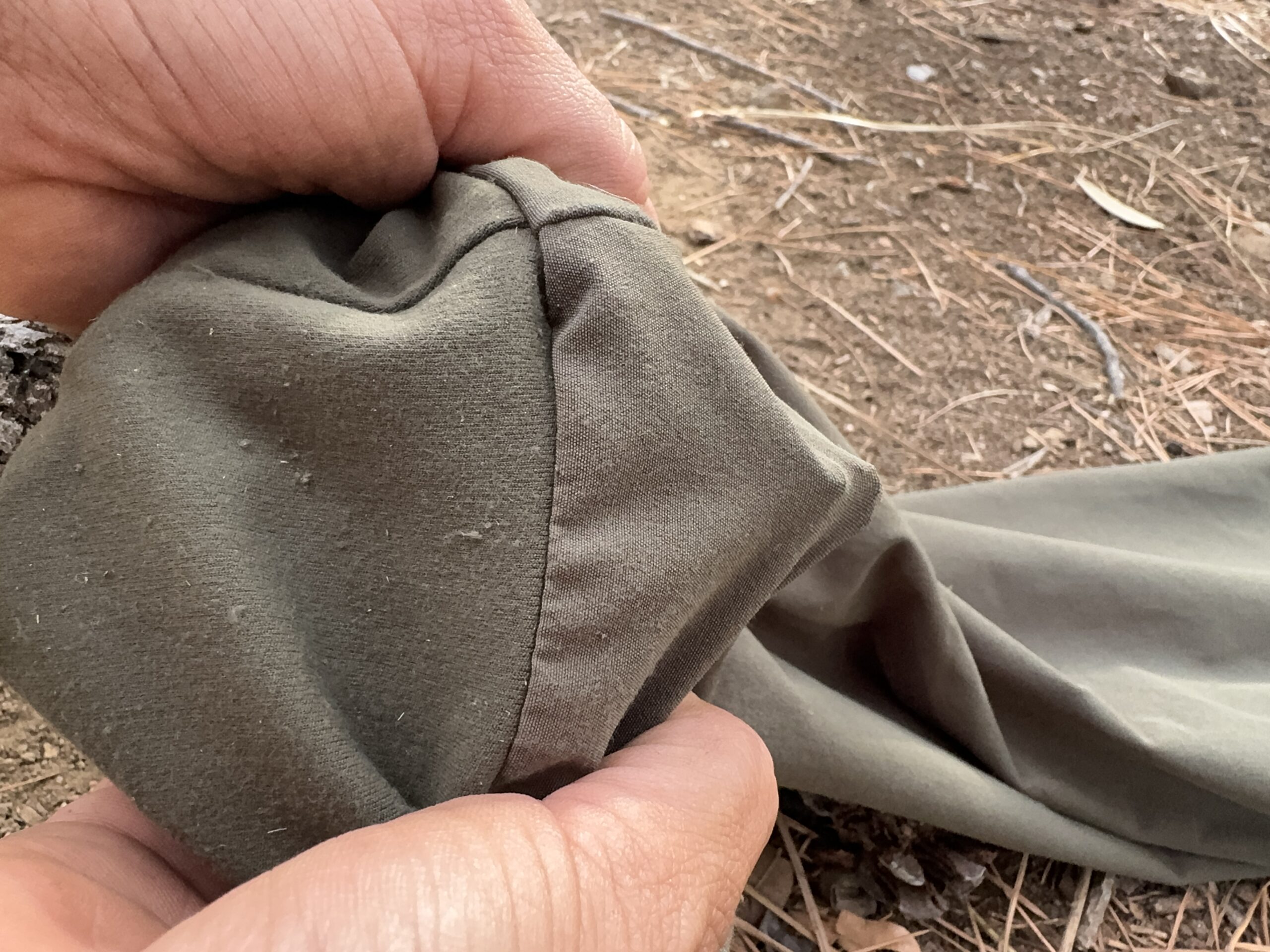 Close up of two hands stretching the fabric of the Patagonia Happy Hike pants over a sharp stick.