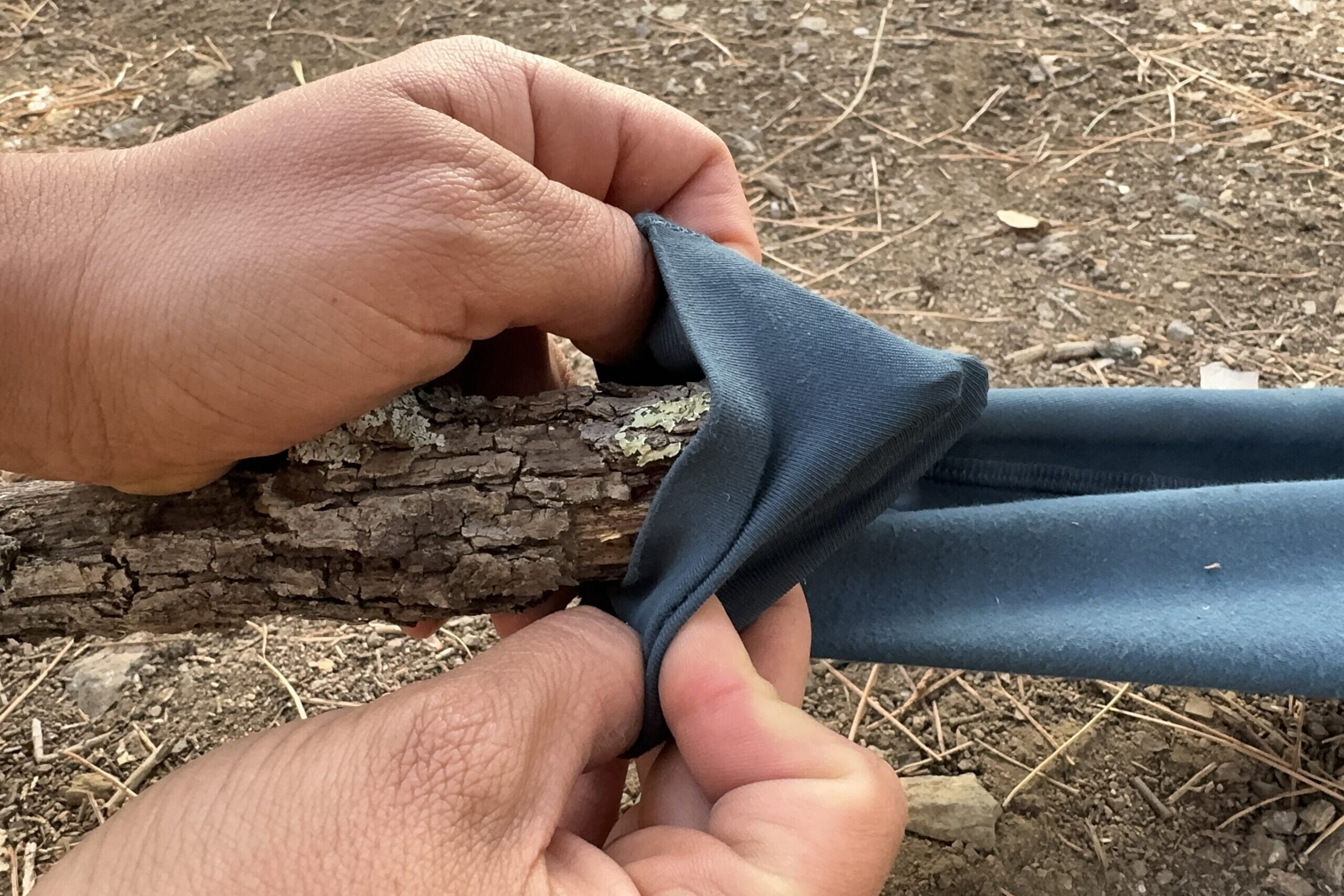 Close up of two hands stretching the fabric of the Abisko pants over a sharp stick.