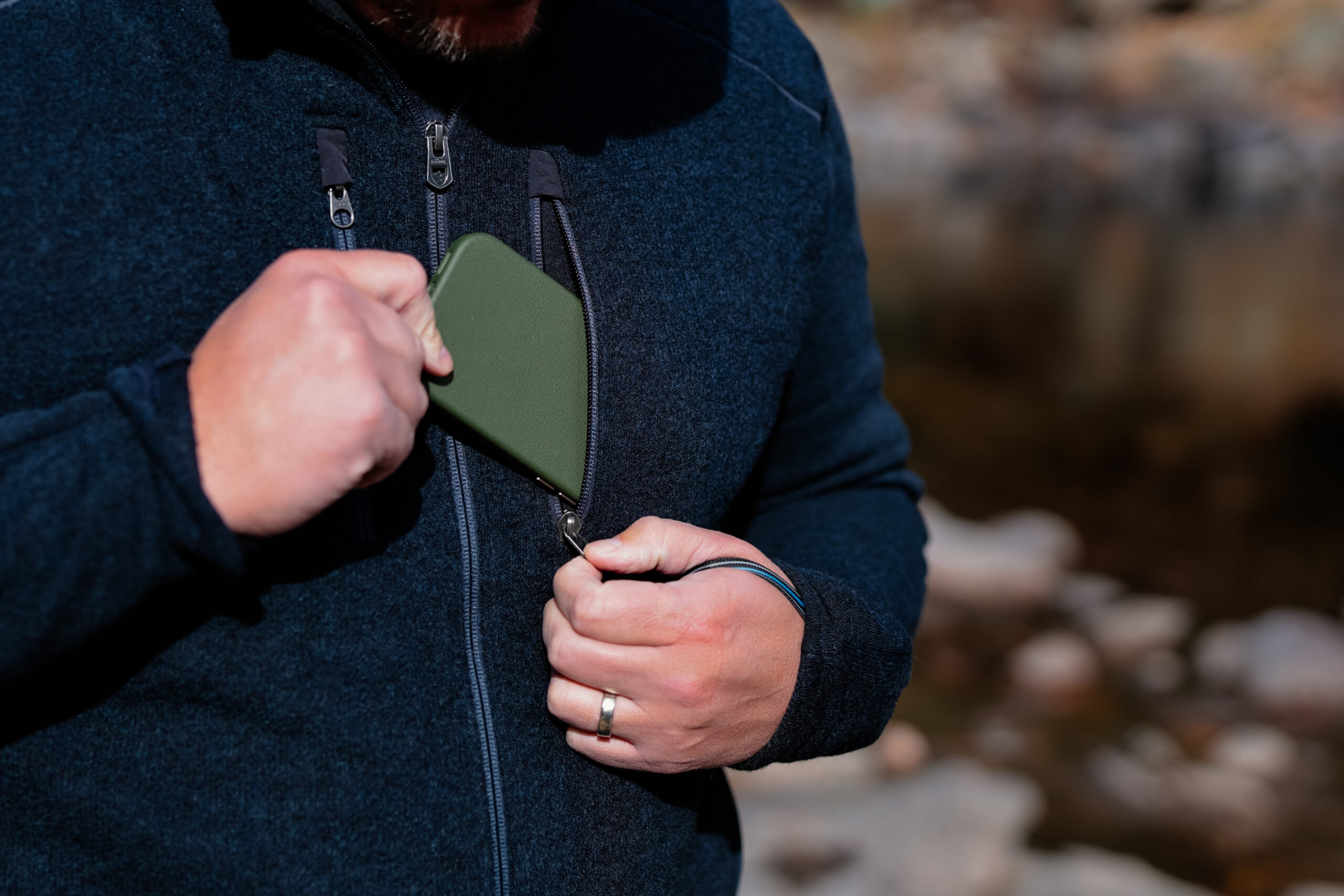 A man pulls a phone from his chest pocket.