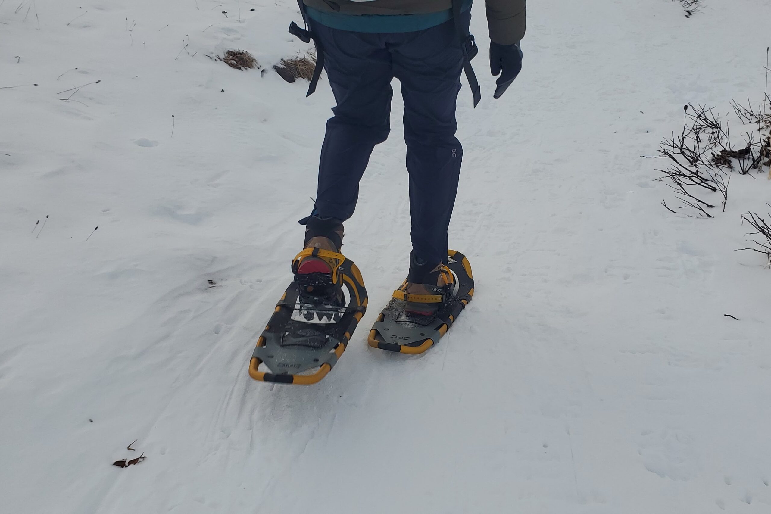 A shot from the back of a person walking while wearing snowshoes.