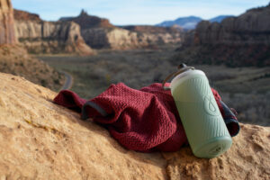 The Hydrapak Flux water bottle rests on a sweater with mesas in the background.
