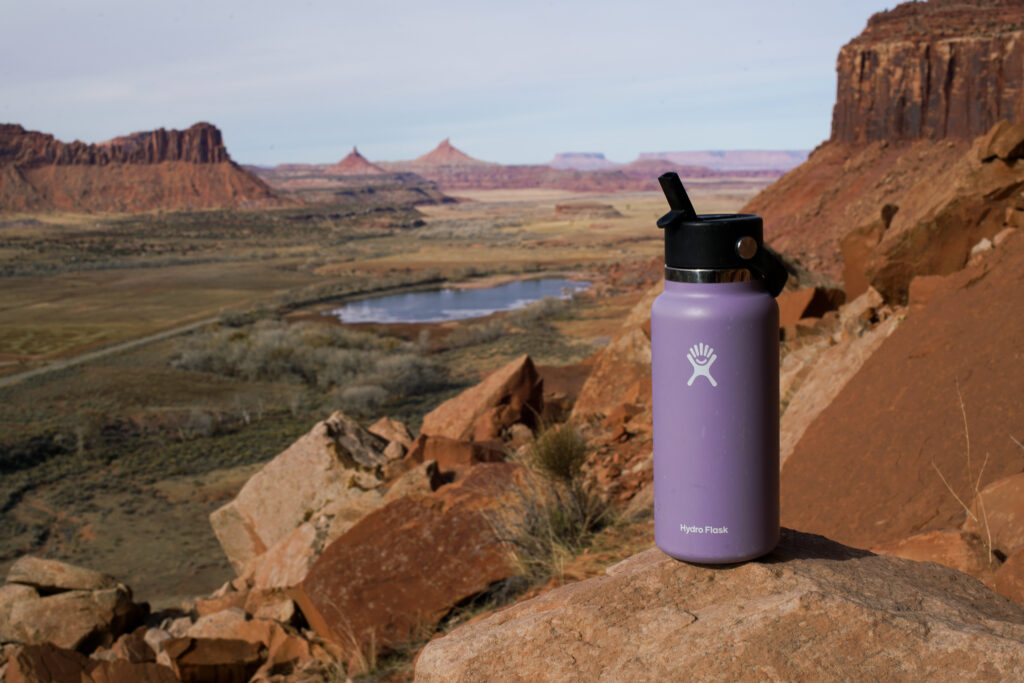 The Hydro Flask Wide Mouth sits on a rock with a lake and mesas in the background.