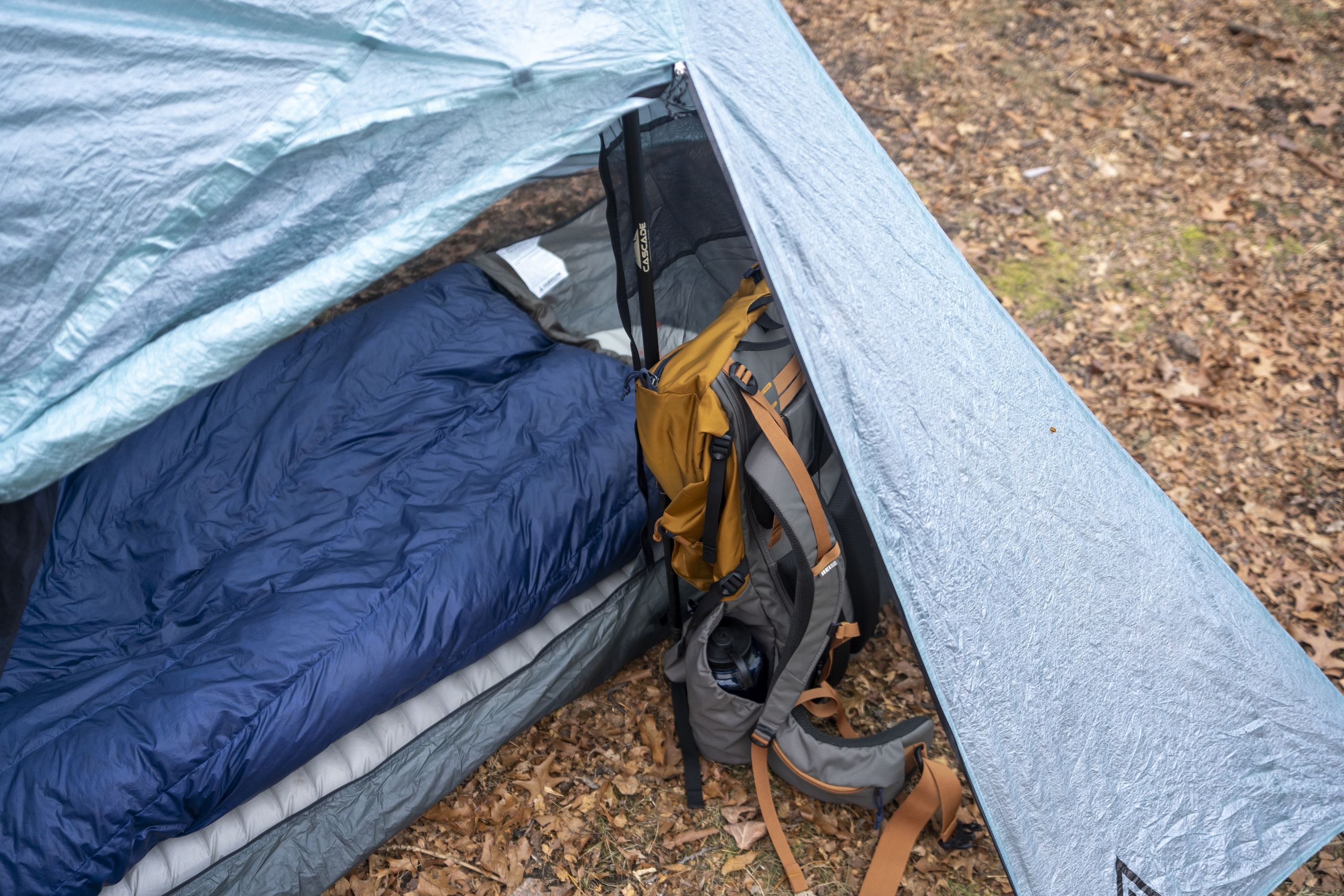 a vestibule of a one person tent holding a backpack
