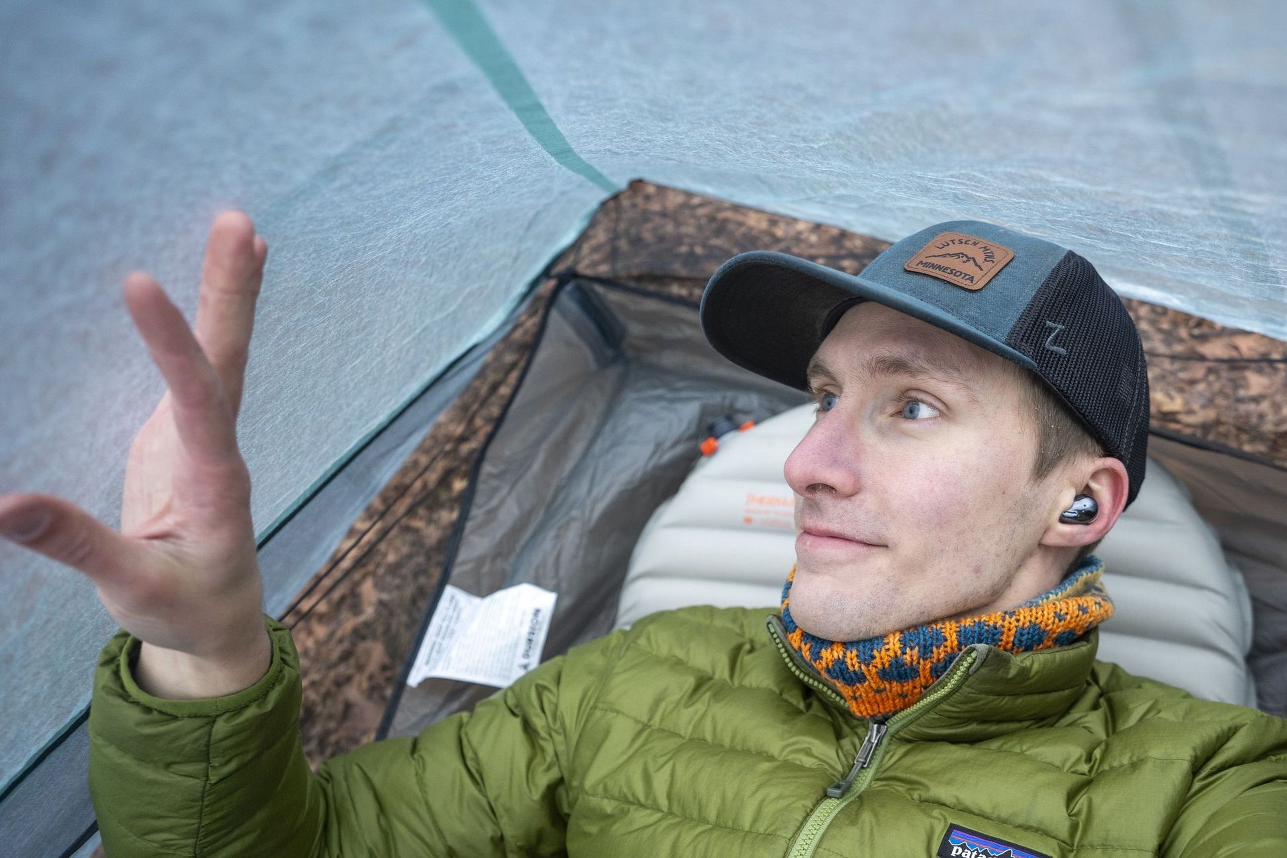 a man lays in a tent and touches the wall