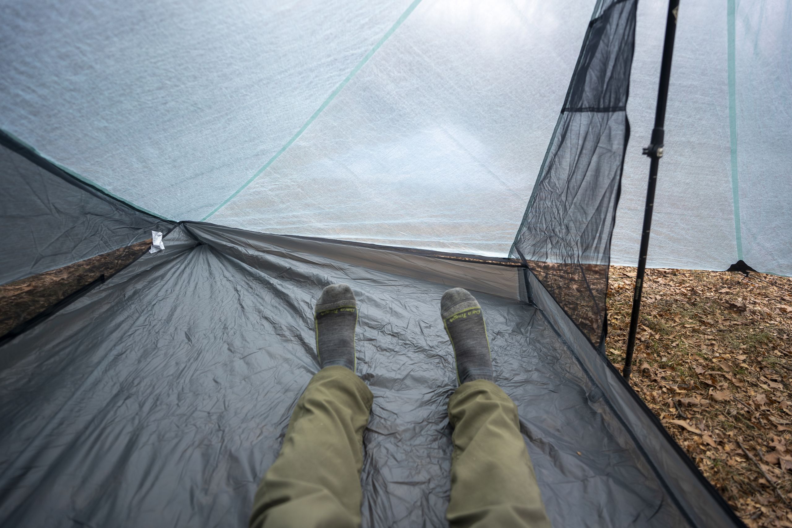 a pair of legs extend into a large two person tent