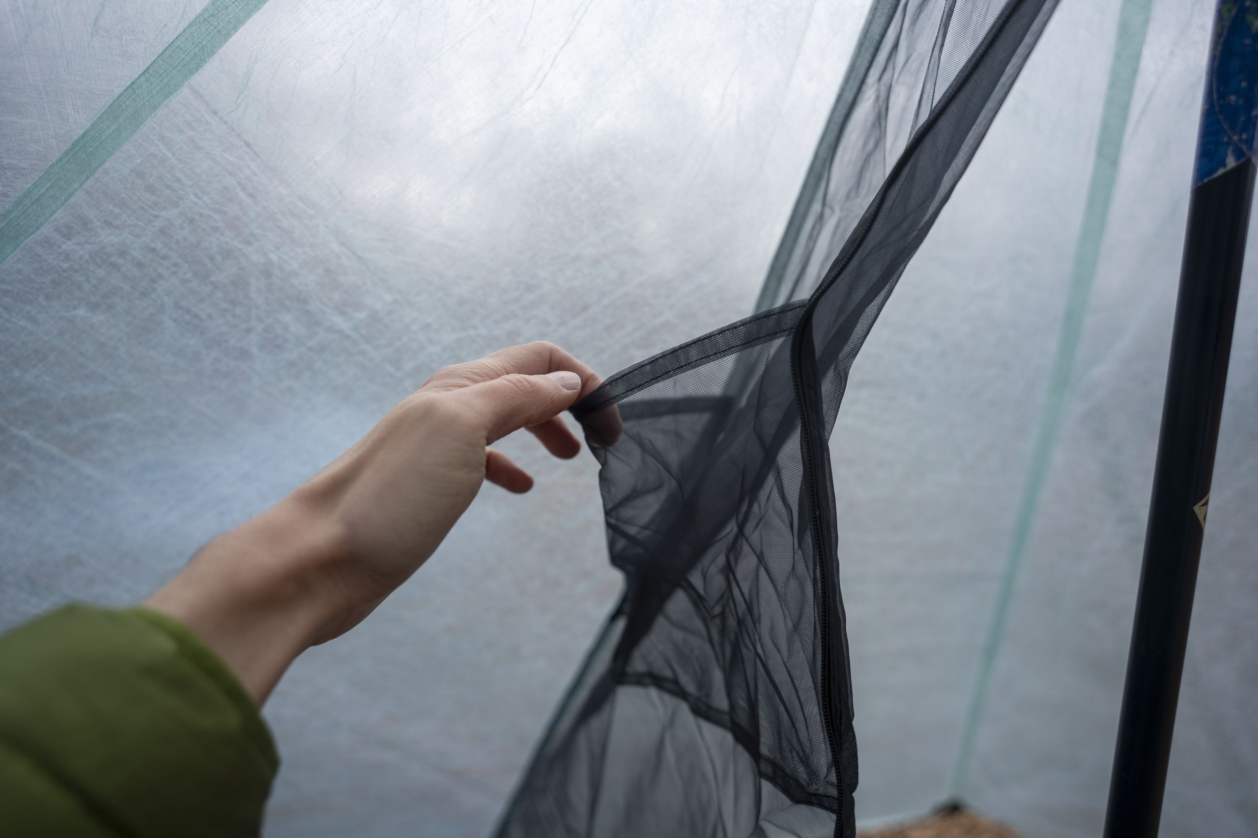 a hand holds open a mesh pocket inside a tent