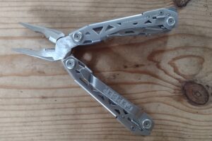The silver Gerber Suspension NXT with its pliers open, on a board.