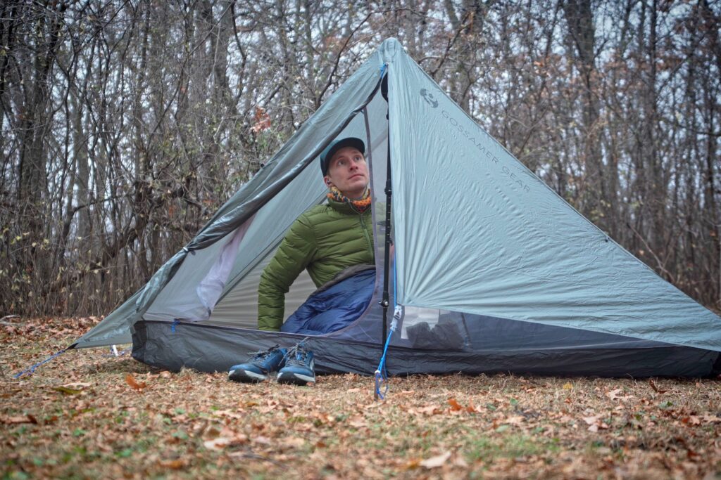 a man in a green coat inside a one person tent