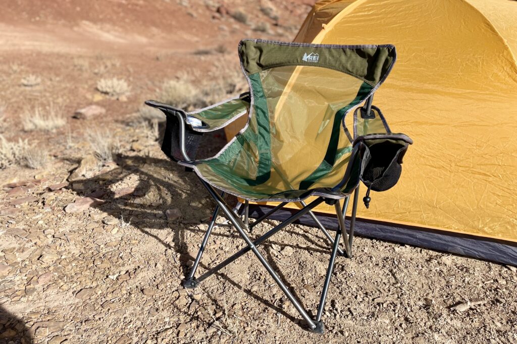 A camping chair in the desert in front of a tent.