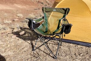 A camping chair in the desert in front of a tent.