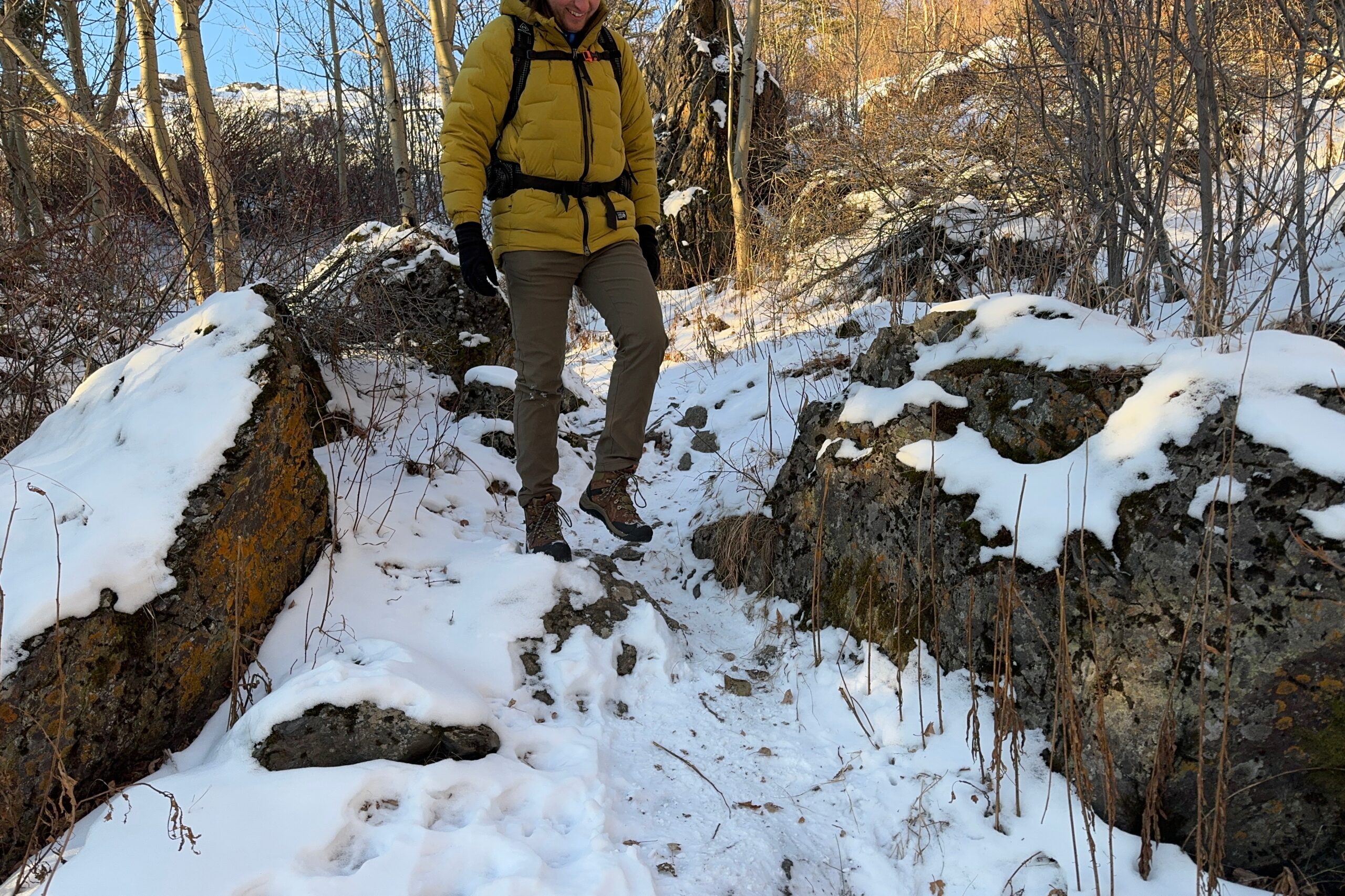 A man walks downhill in winter boots.