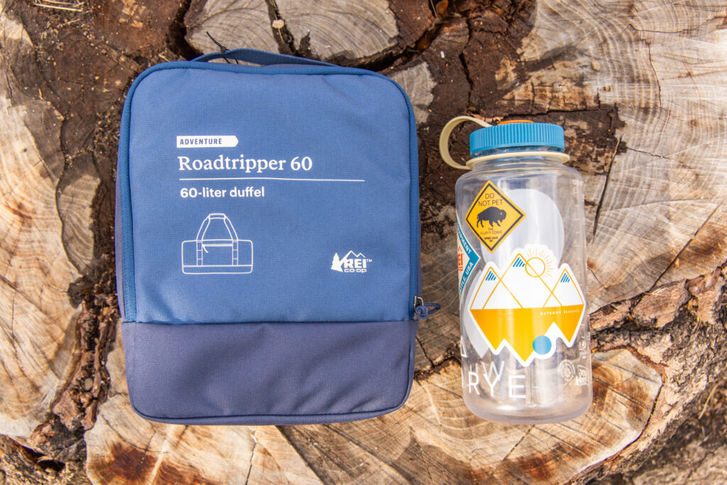 The REI Roadtripper Duffel packed into its separate storage pouch and placed next to a Nalgene for size comparison.