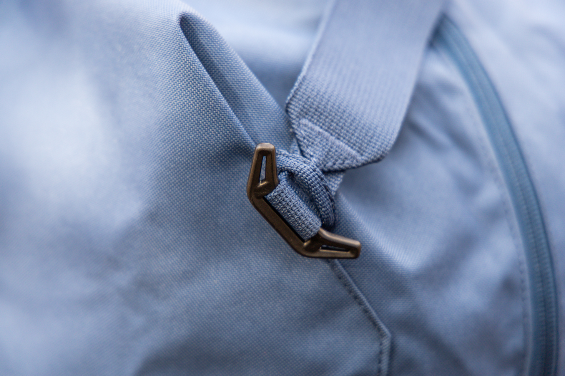 The plastic hook and webbing loop used to attach the removable shoulder strap to the bag.