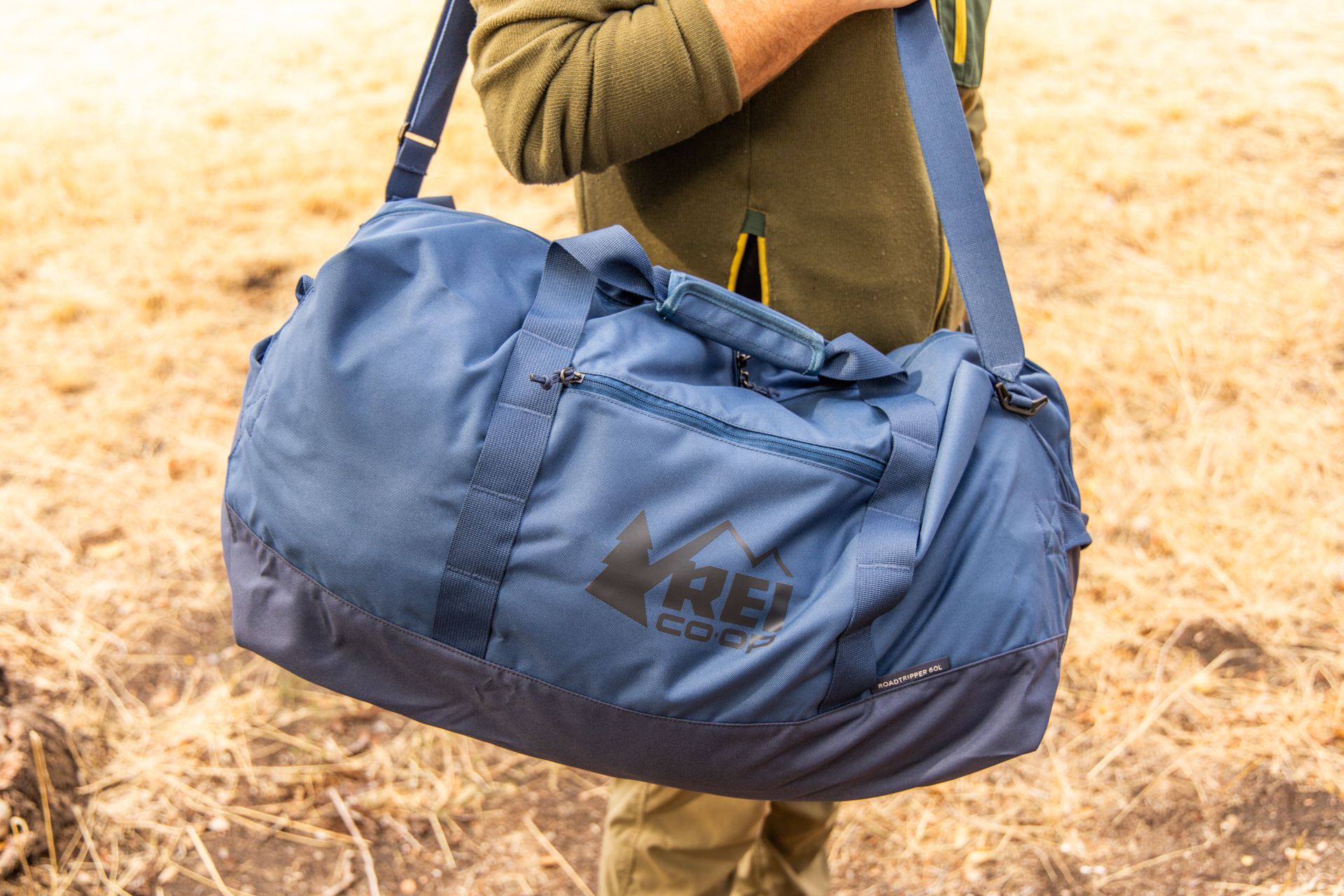 A man carries the Roadtripper duffel over his shoulder using the removable strap.
