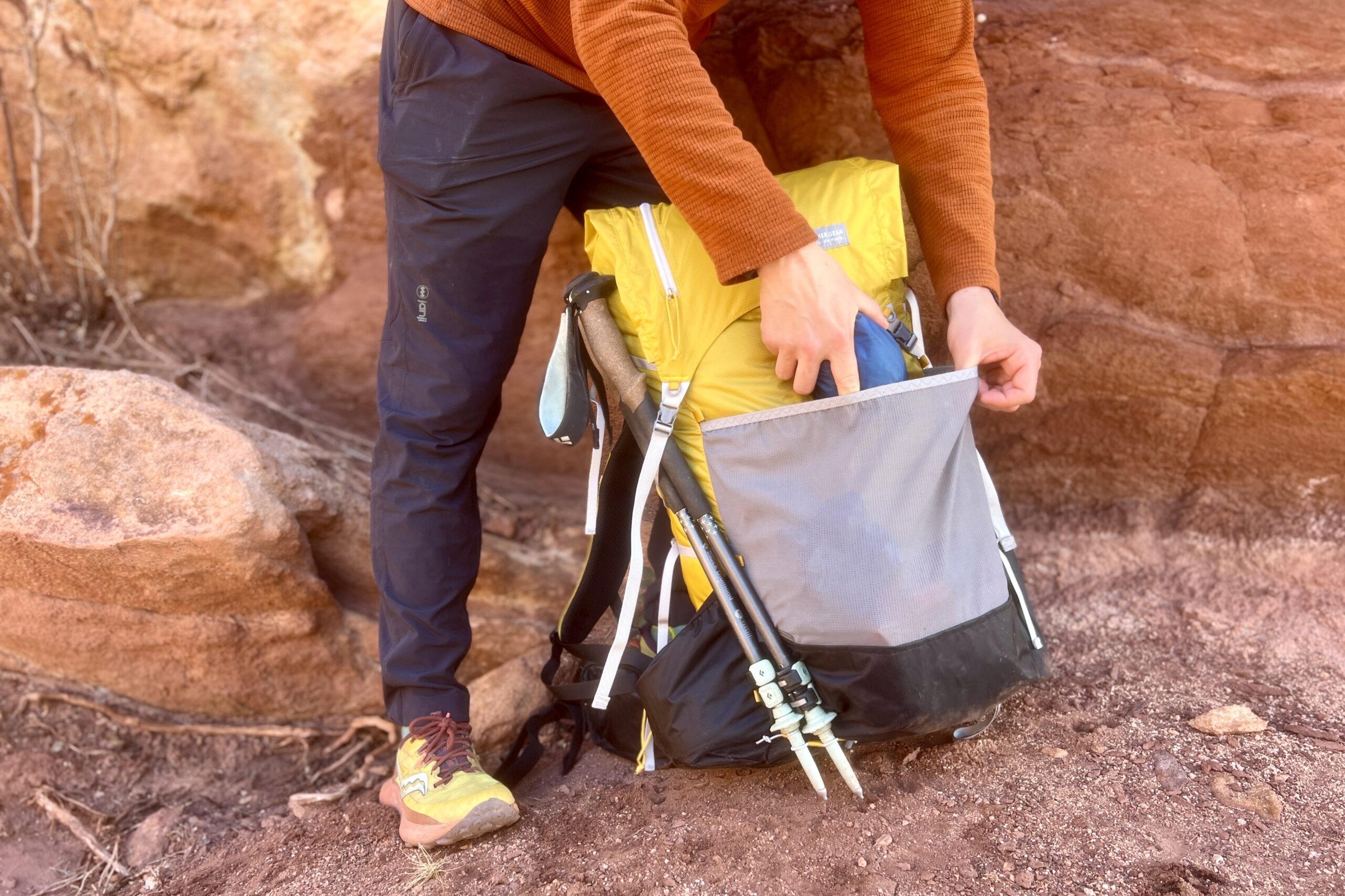 A person pull something out of the front mesh pocket of the Gorilla 50 with red rock in the background.