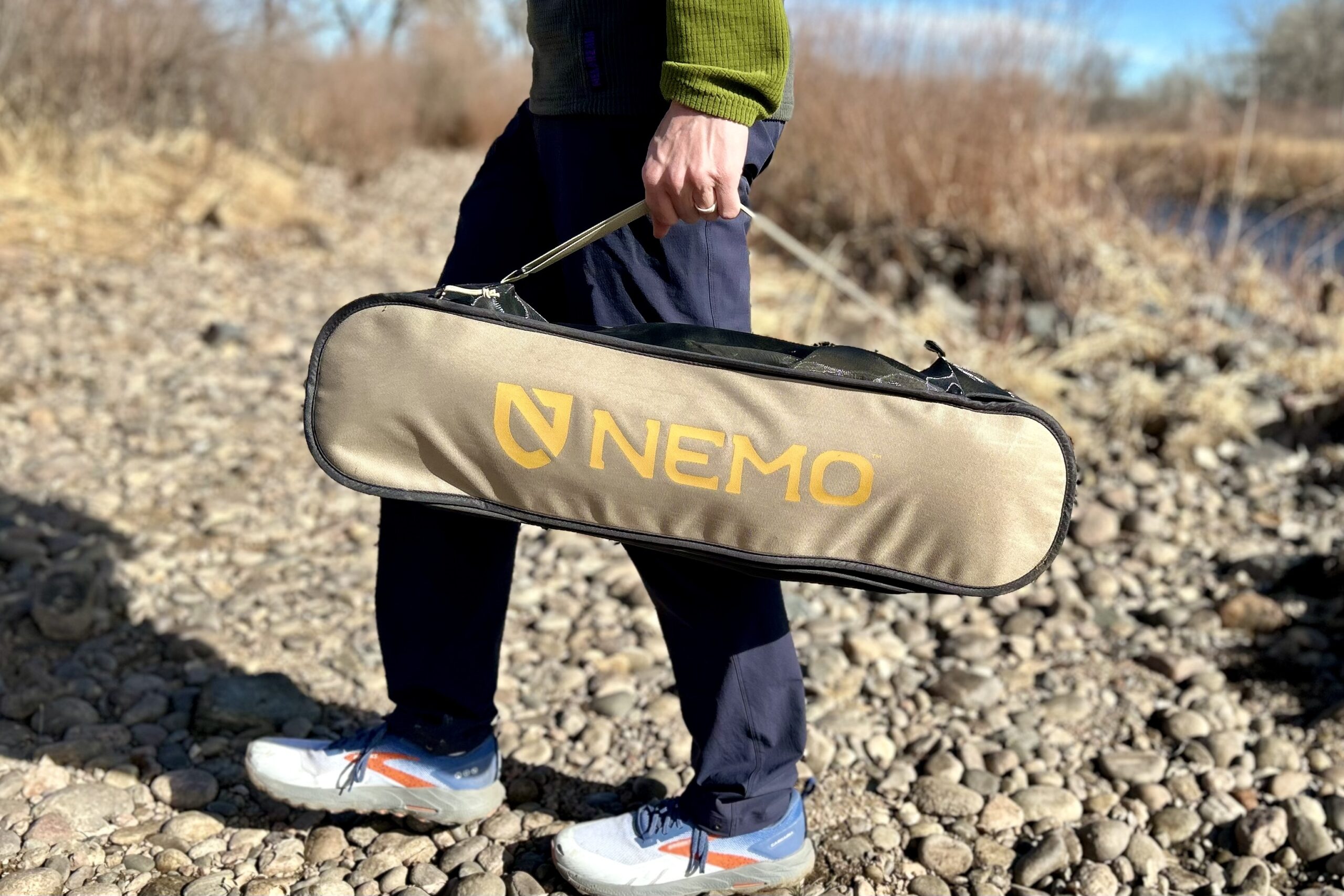 Close up of a person carrying a camping chair in it's case.