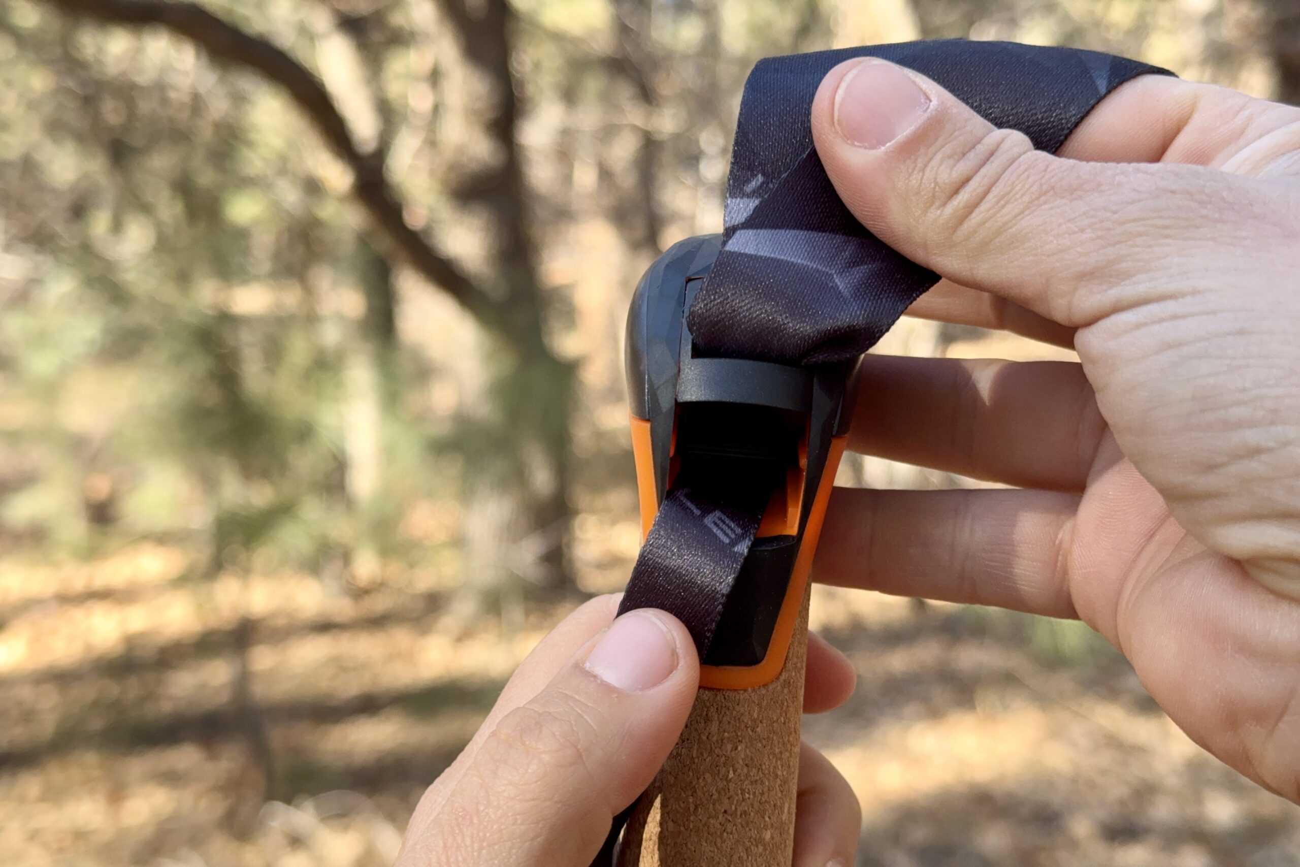 A close up of the Leki Air Grip wrist strap tightening system with a forest in the background.