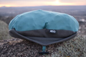 Close up of the REI Trailmade Pillow on a boulder as the sun sets in the background. The pillow looks lumpy due to the foam blocks inside.