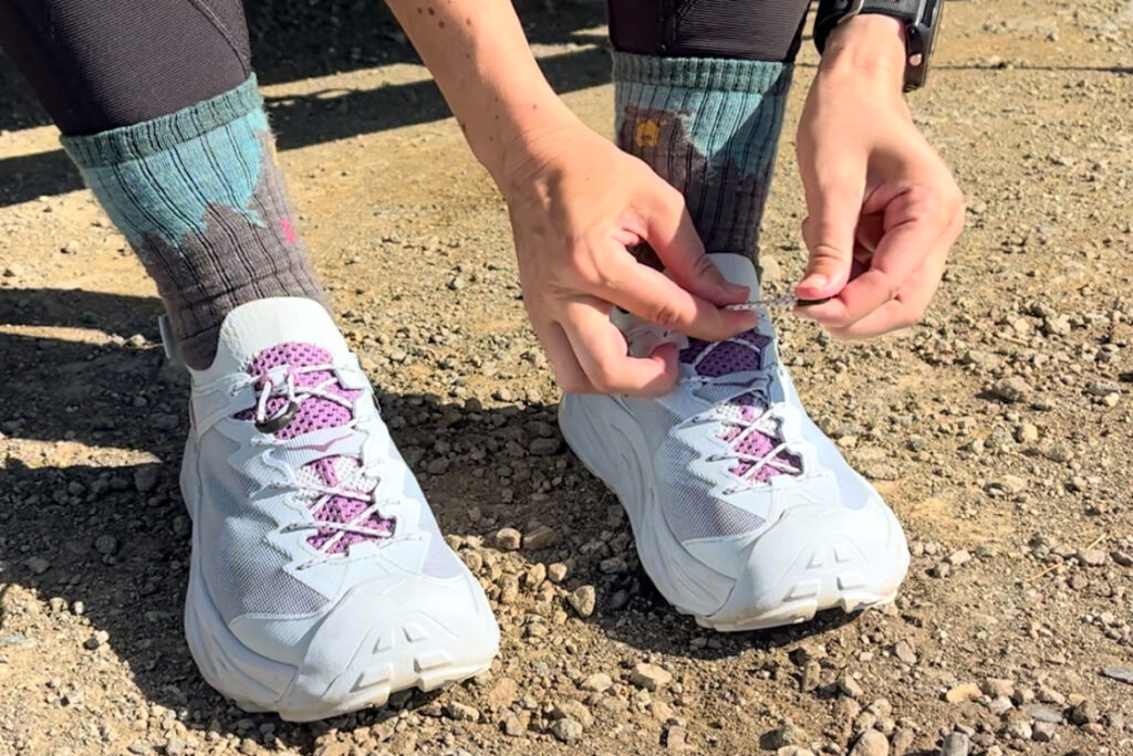 Our tester putting on the HOKA Hopara 2 sandals on a hike.