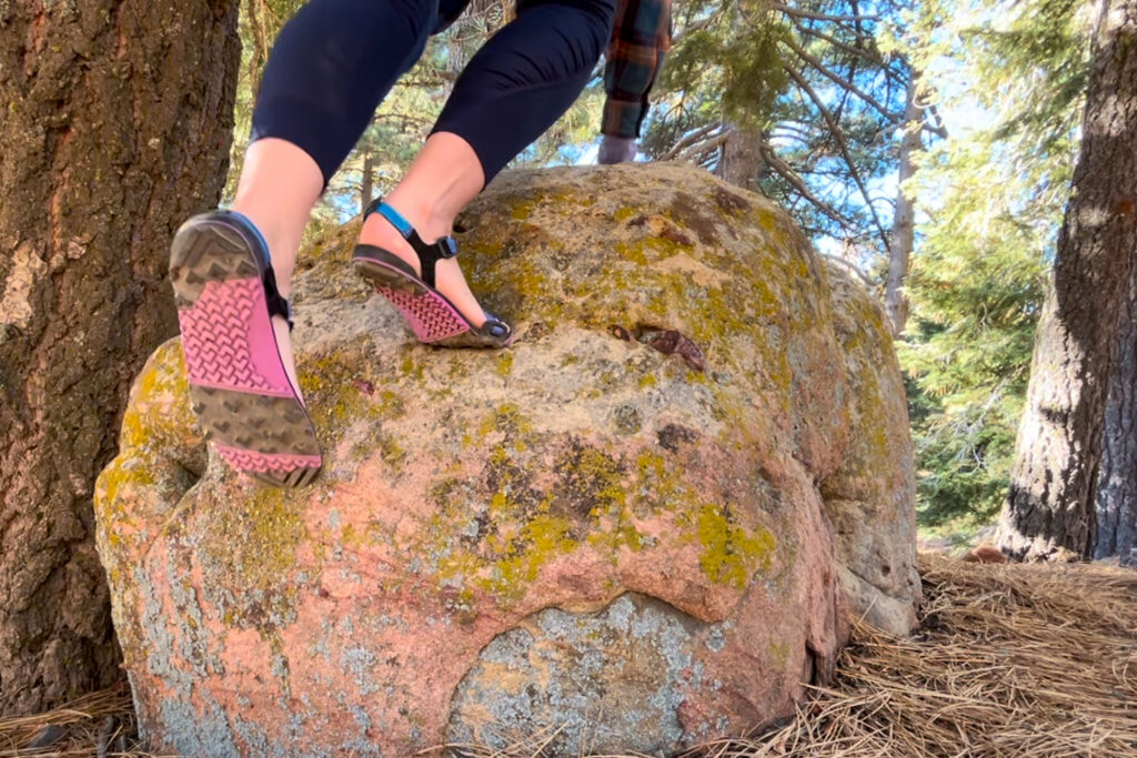 Our hiker climbing over a boulder in the Xero Shoes Z-Trail EV hiking sandals.