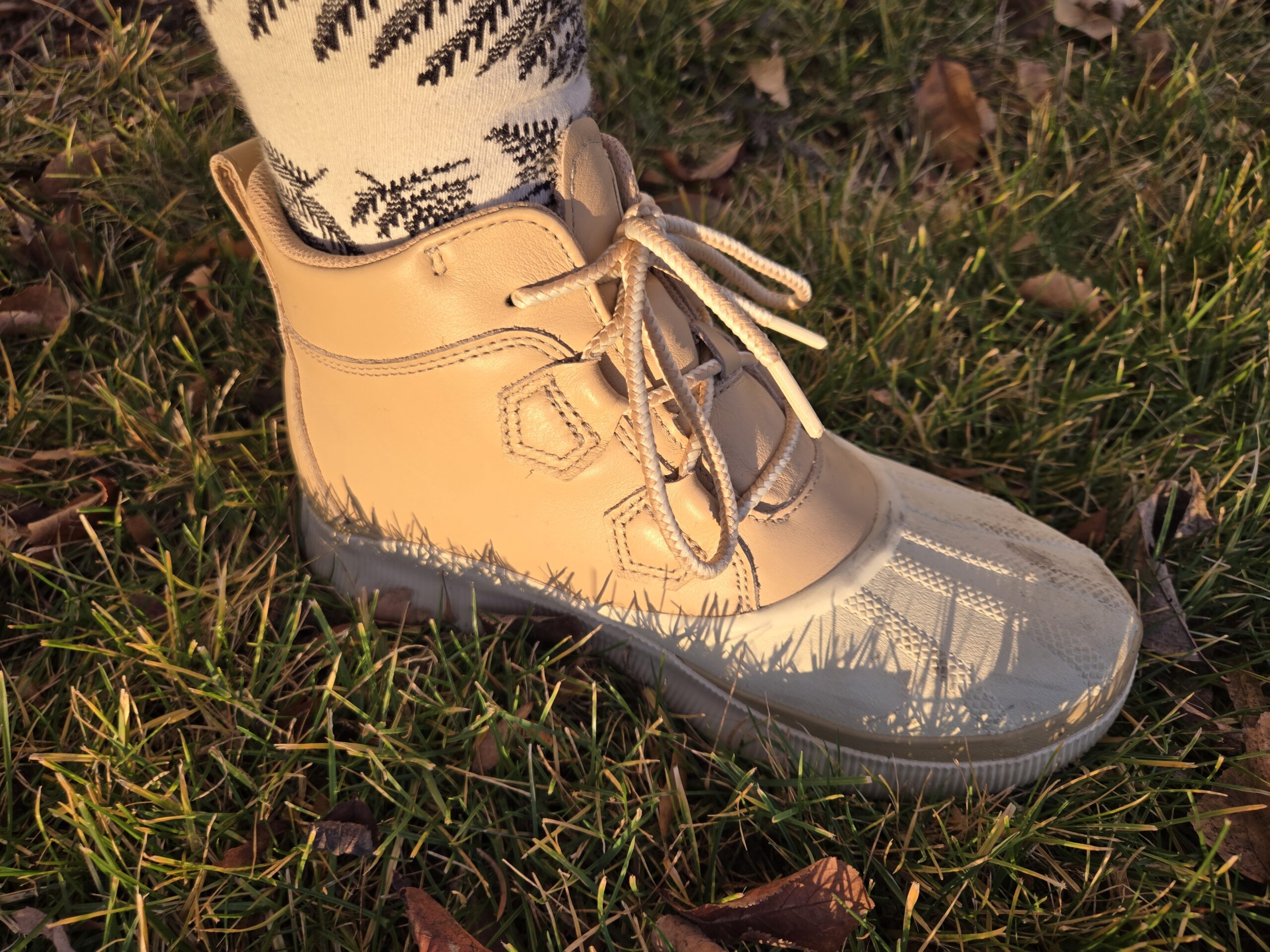 Sunshine hits the side of the Sorel Out N About IV boot in a grassy field.