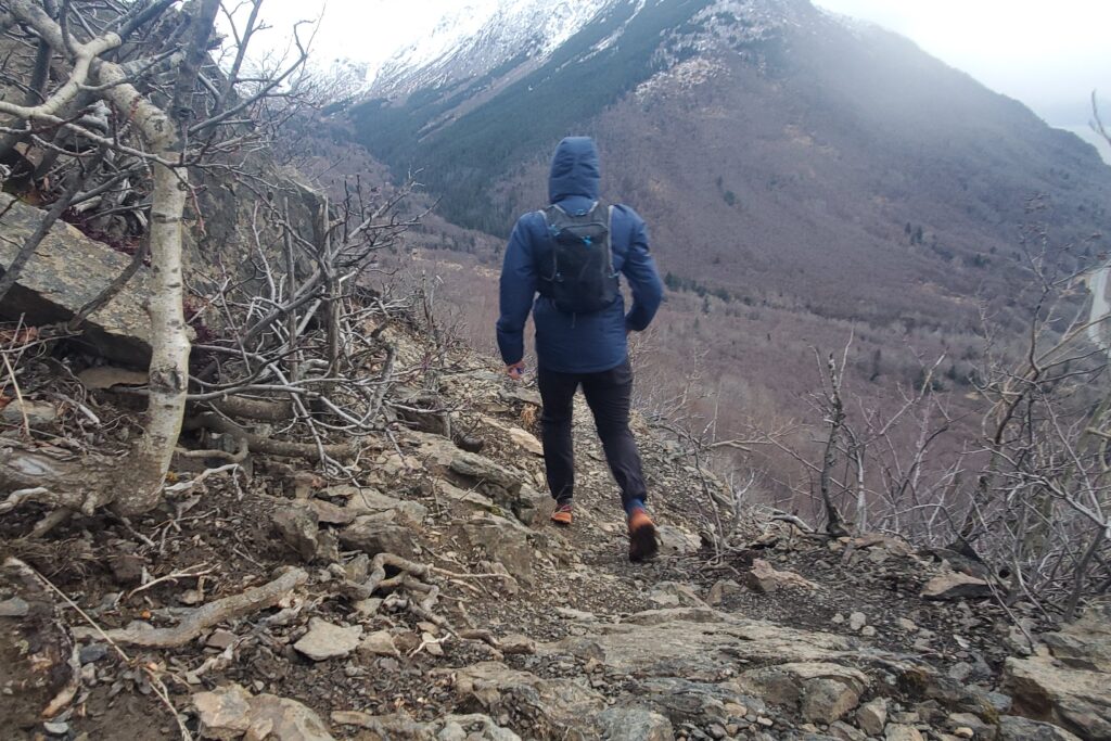 A man hikes downhill in front of a mountain vista.