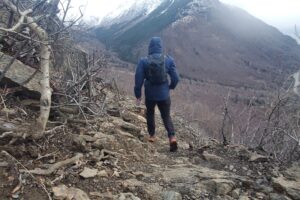 A man hikes downhill in front of a mountain vista.