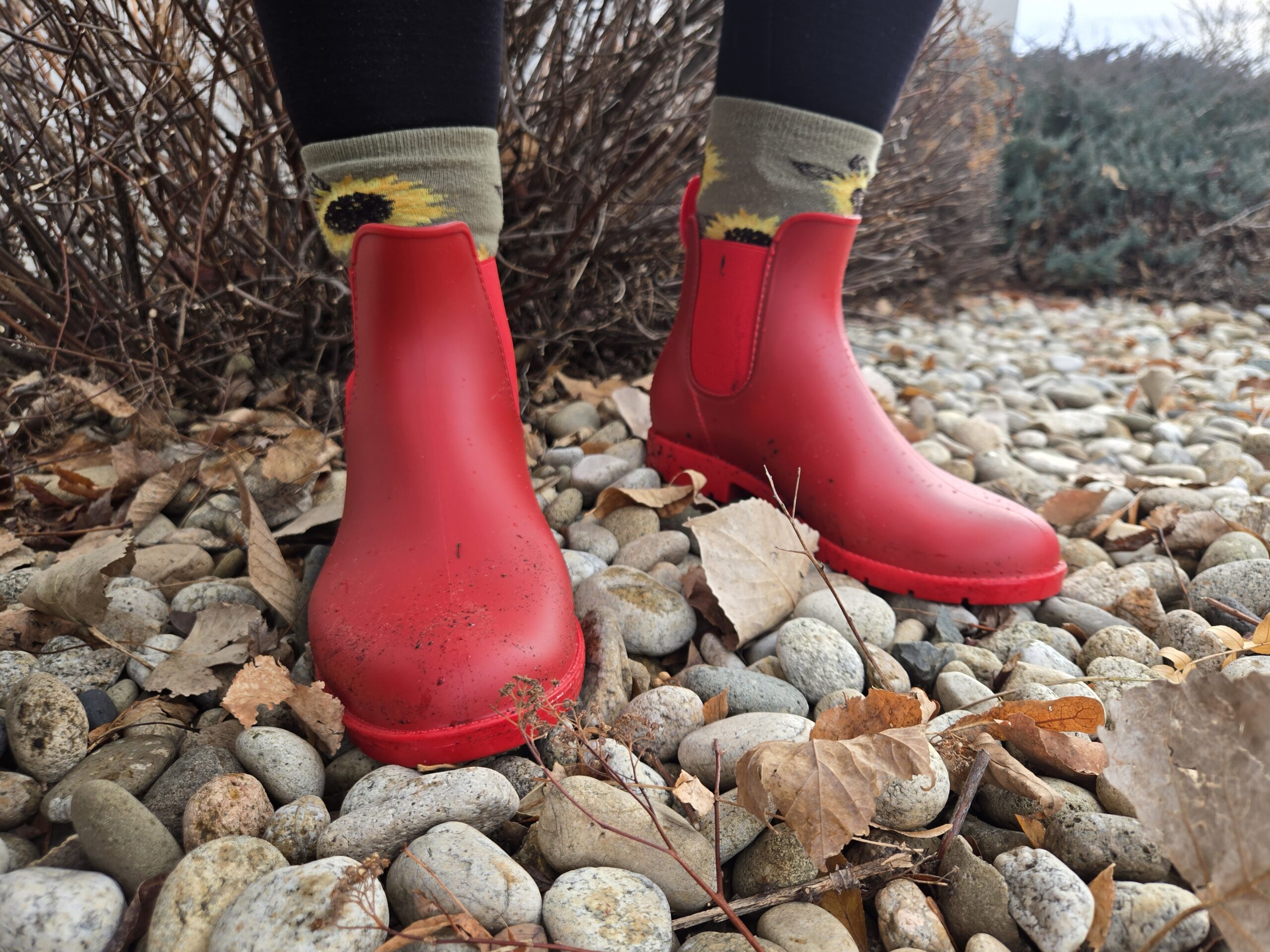 a woman standing on river rock cobble wearing asgard chelsea rain boots