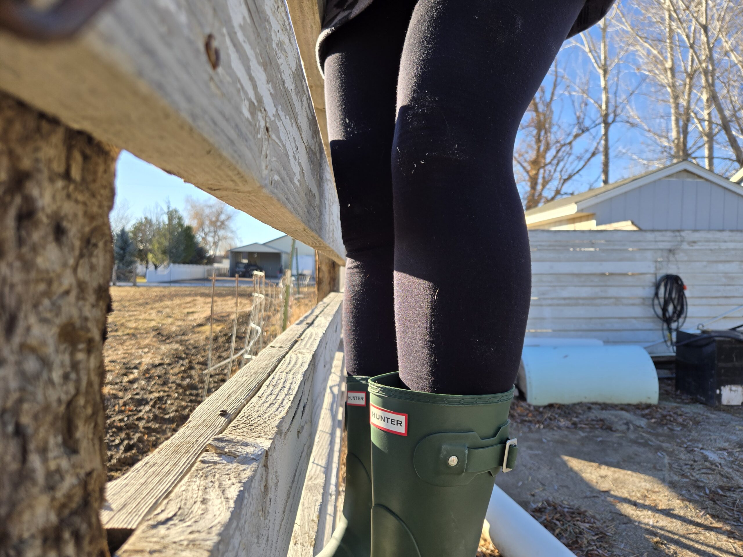 women on a fence in hunter orginial boots