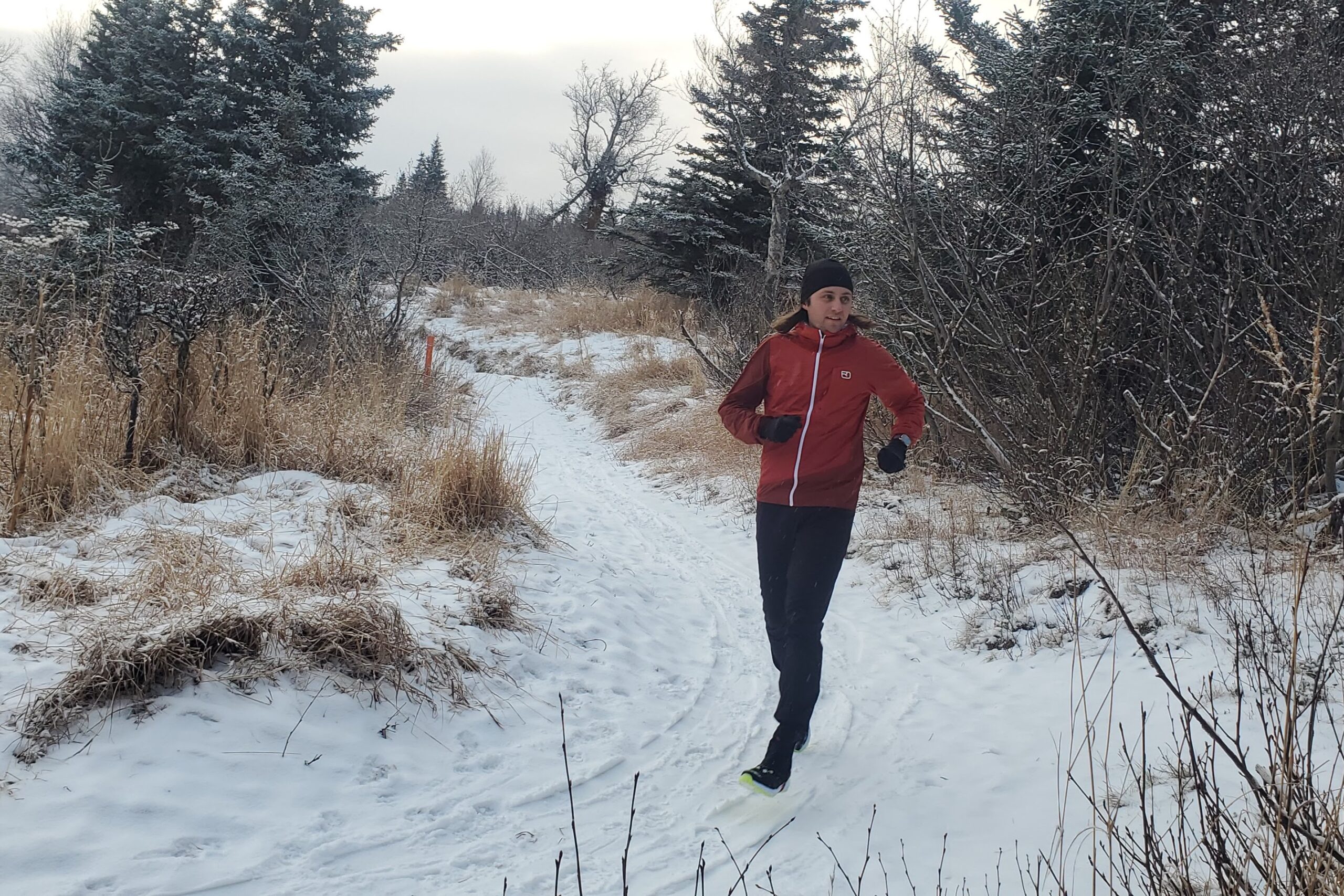 A man runs down a snow covered trail.