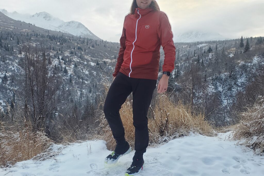 A man stands in front of a snowy canyon view.
