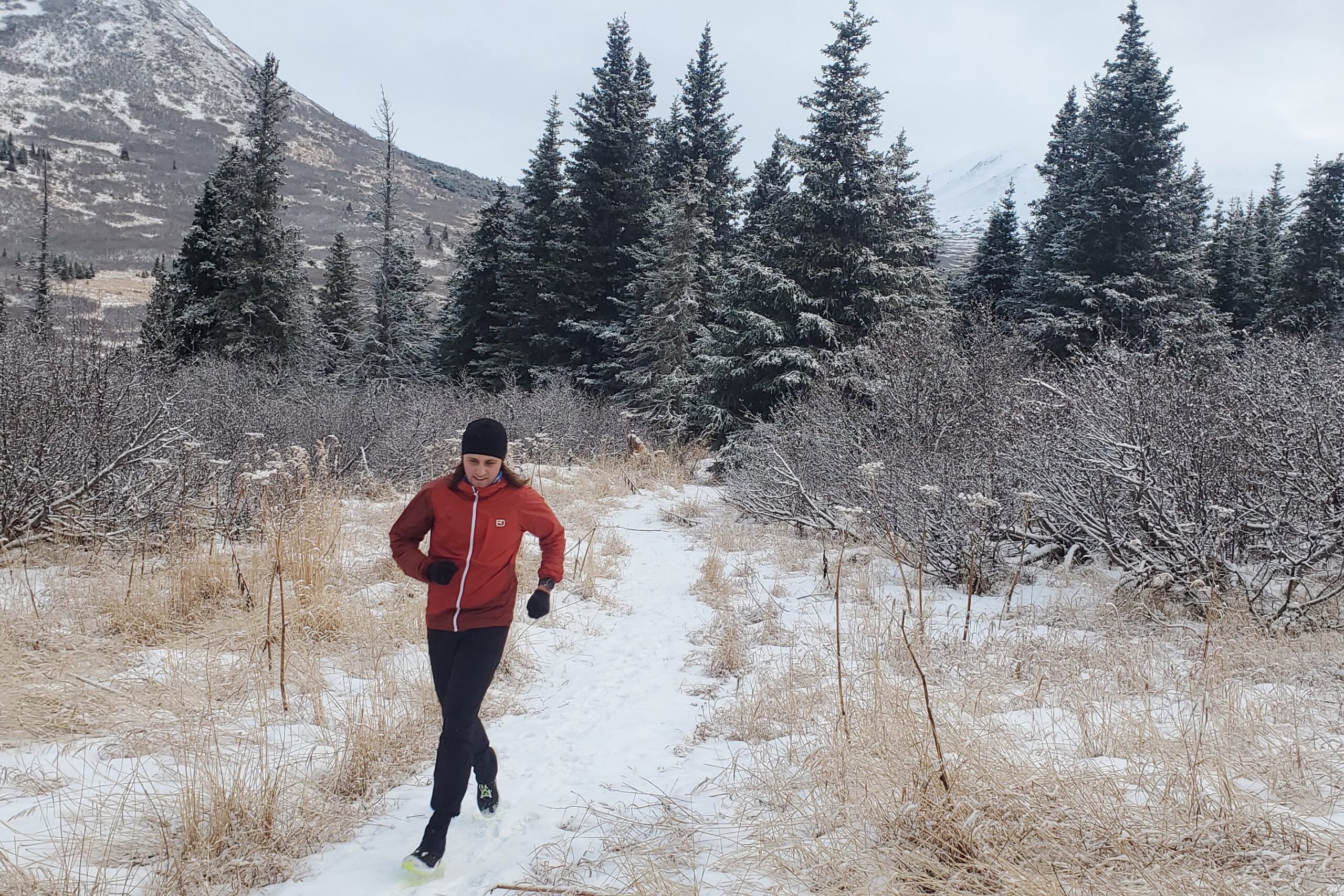 A man runs through a snowy forest.