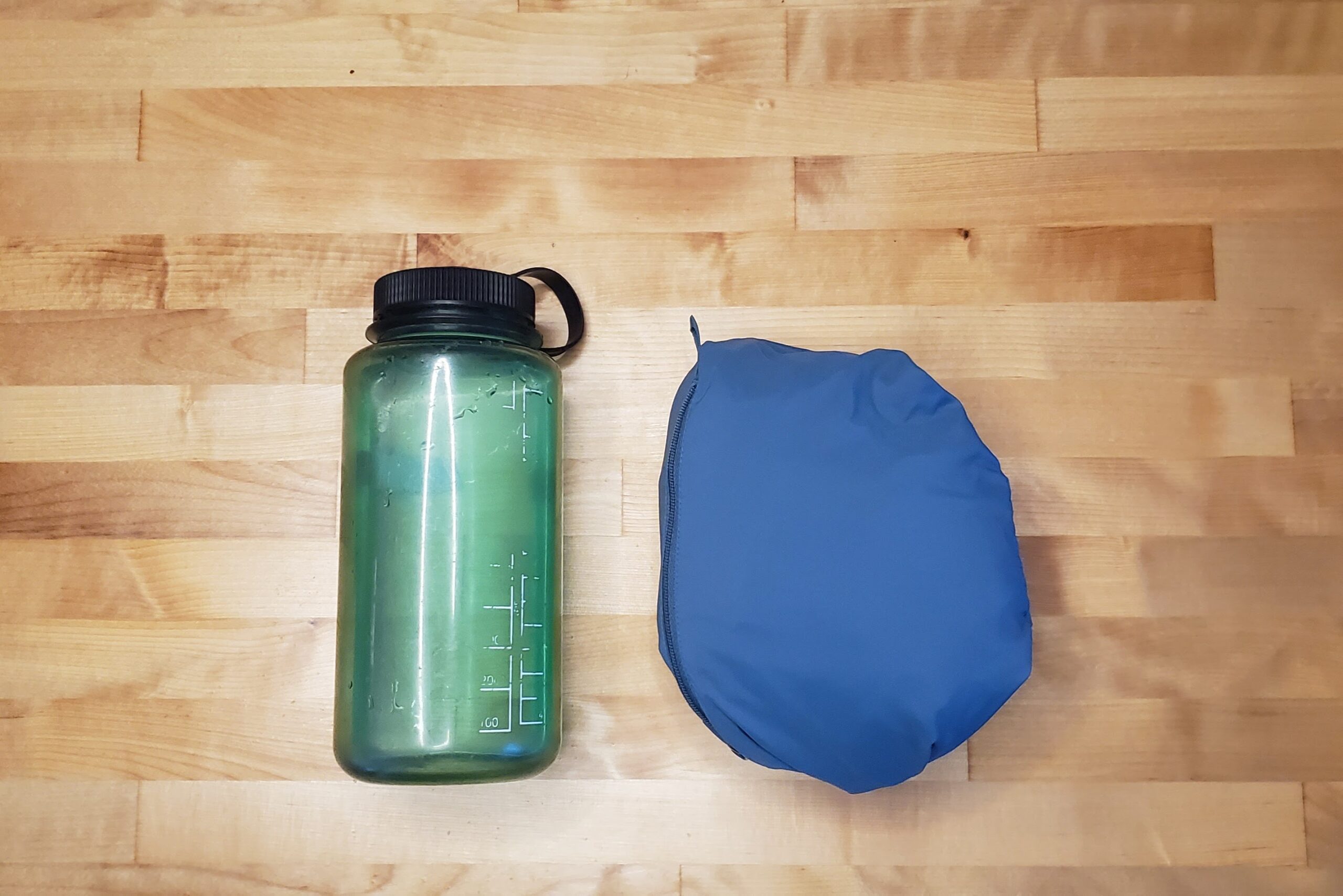 A jacket stuffed into a ball compared to a one liter bottle.