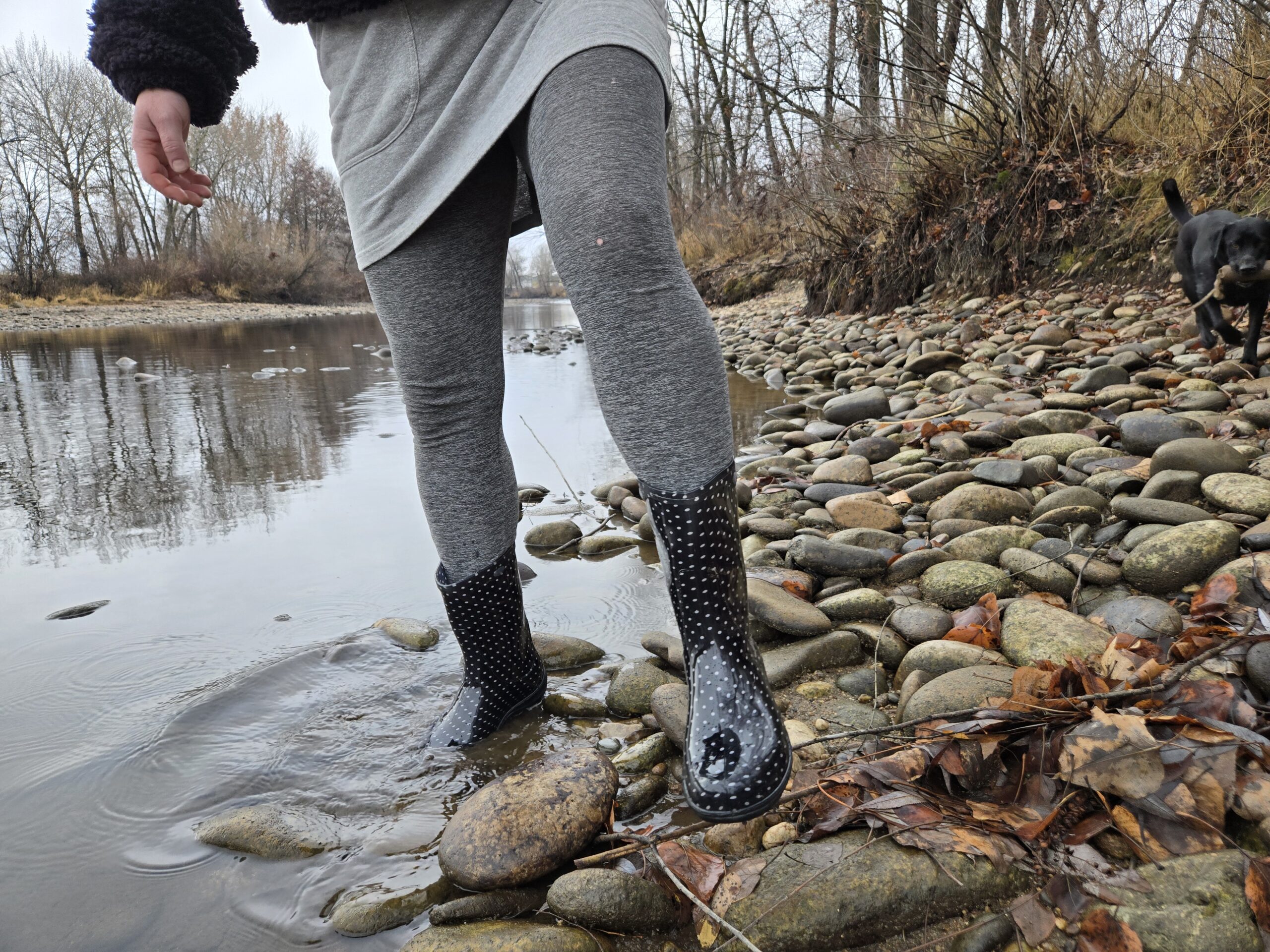 a woman walking along a river bed with one foot in the water