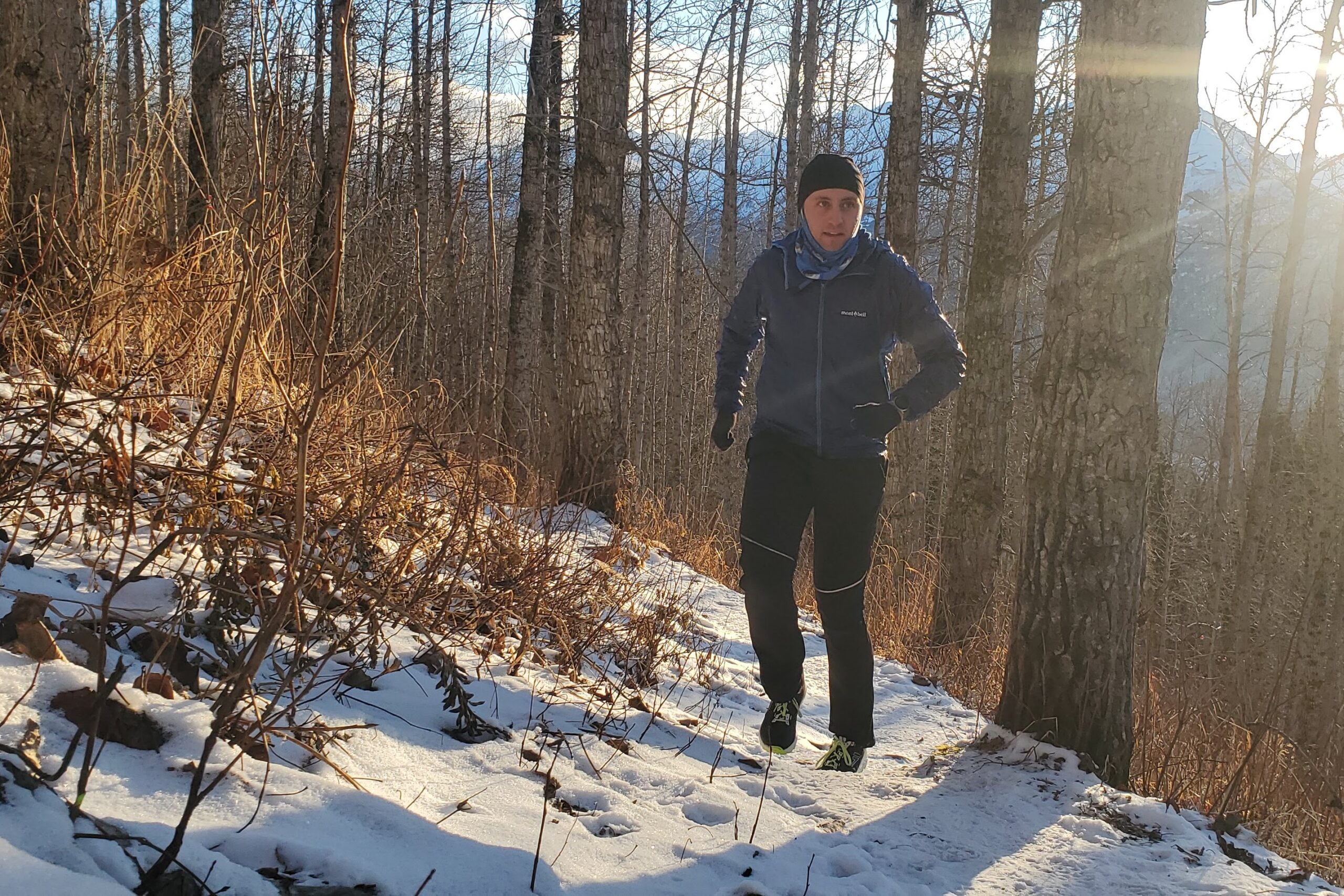 A man runs up a snowy trail.