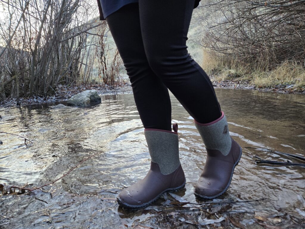 woman standing in a small stream in muck boots