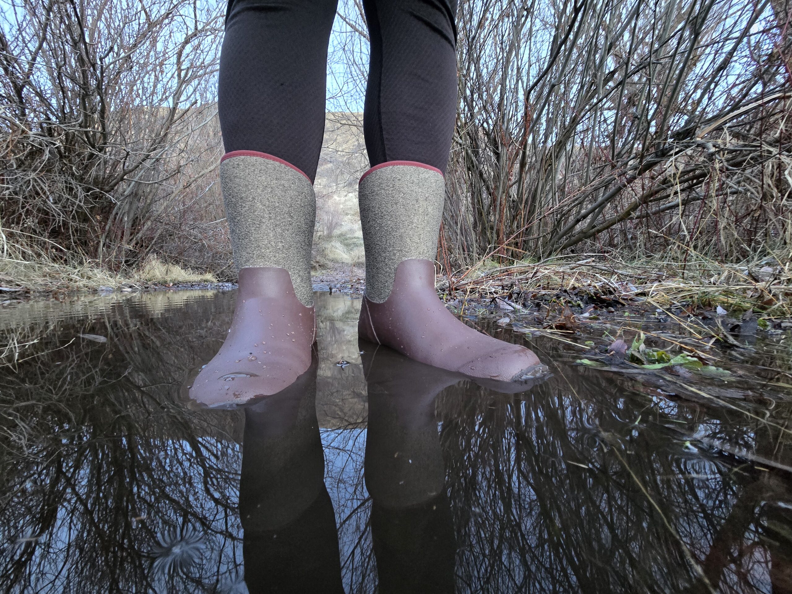 woman standing in a puddle in muck boots