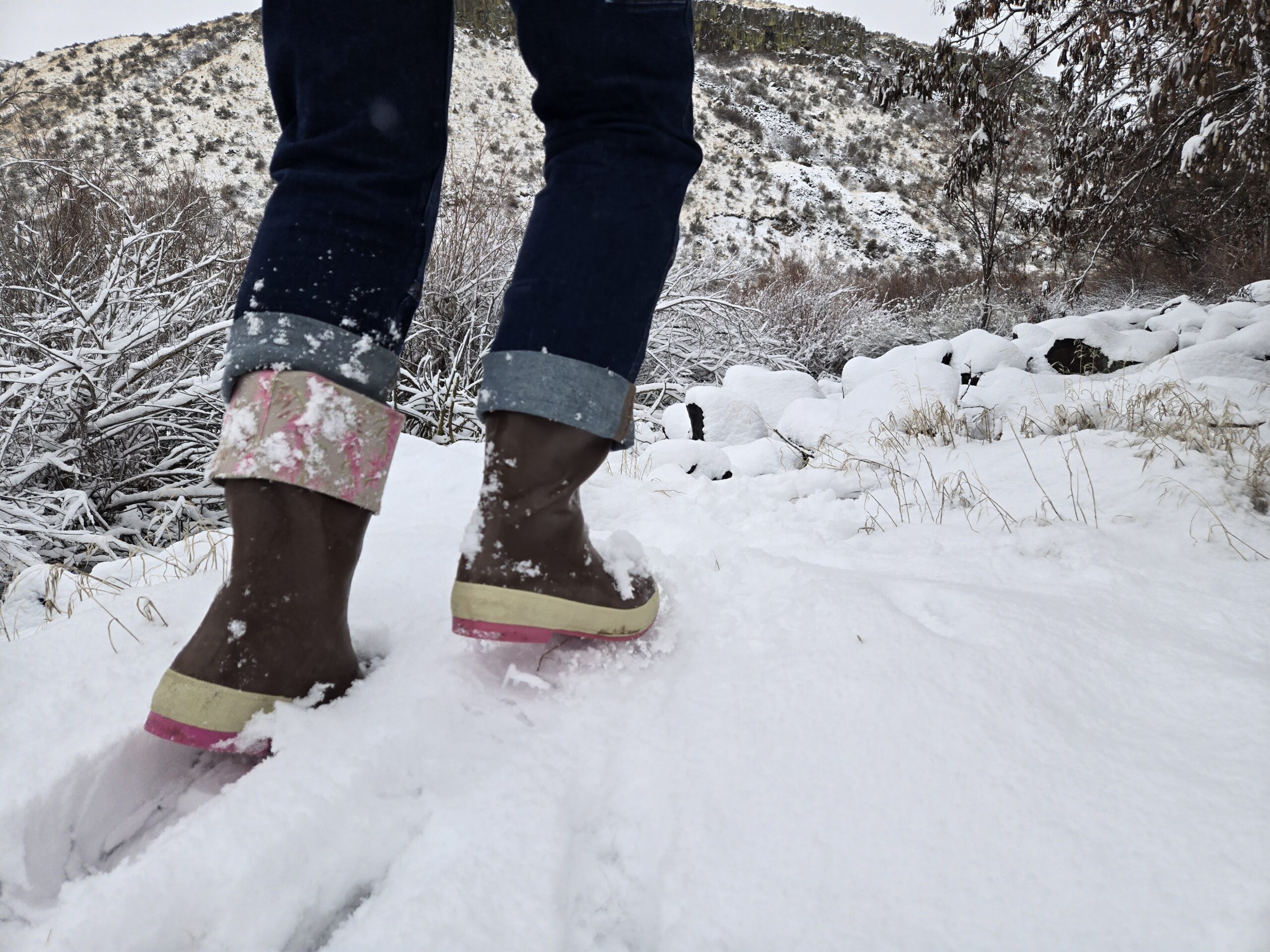 woman walking in the snow wearing xtratuf boots