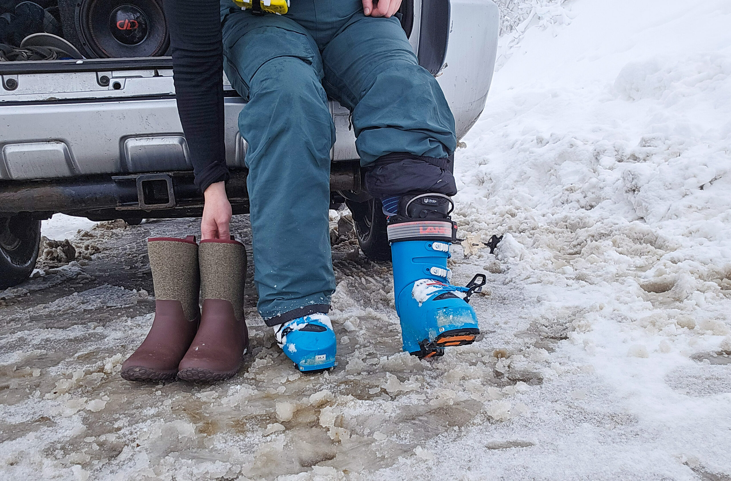 women sitting on her tailgait switching from ski boots to muck boots