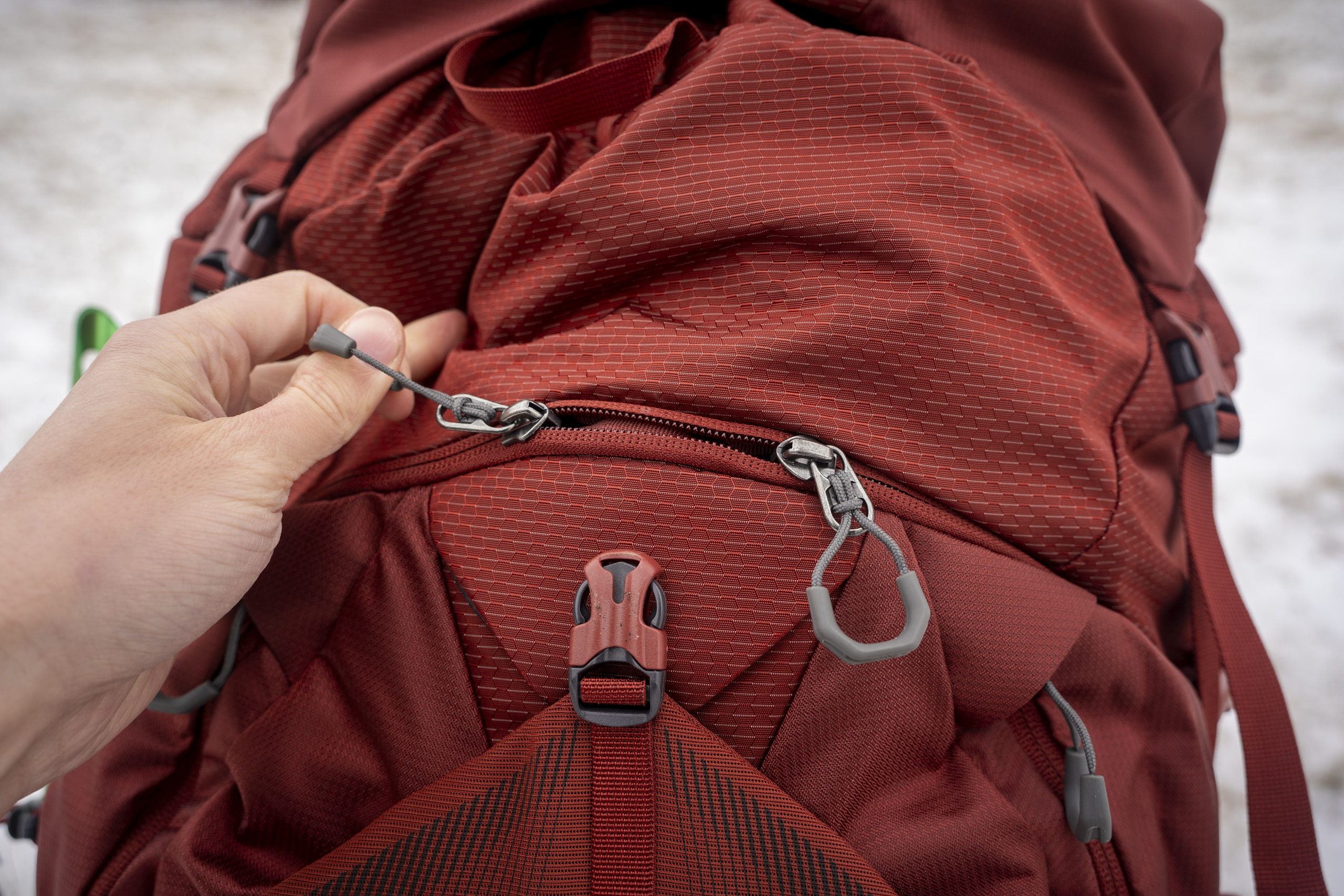 a hand holds a zipper on a backpack