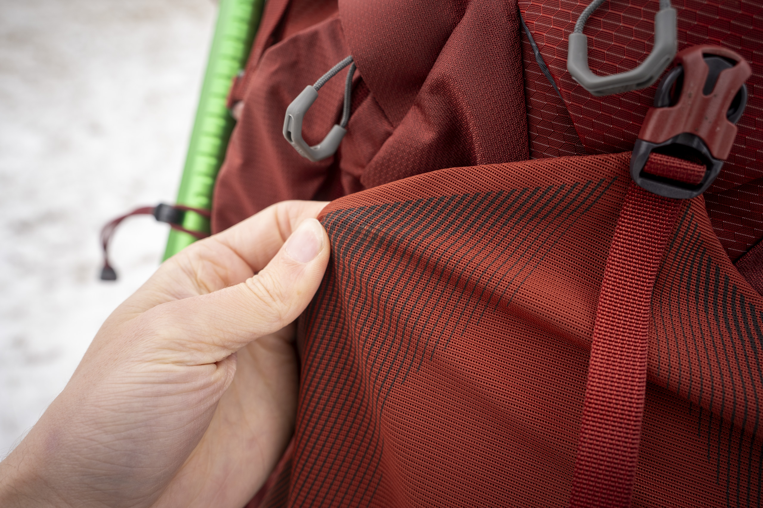 a hand holds red mesh of a backpack
