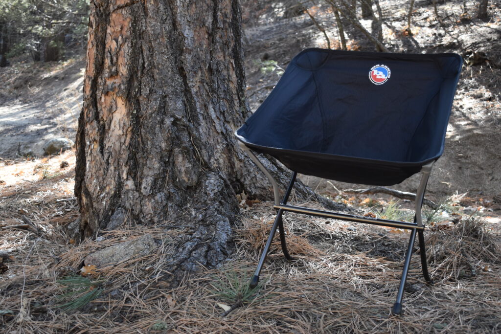 The Skyline Chair sits fully assembled next to the trunk of a lodgepole pine tree